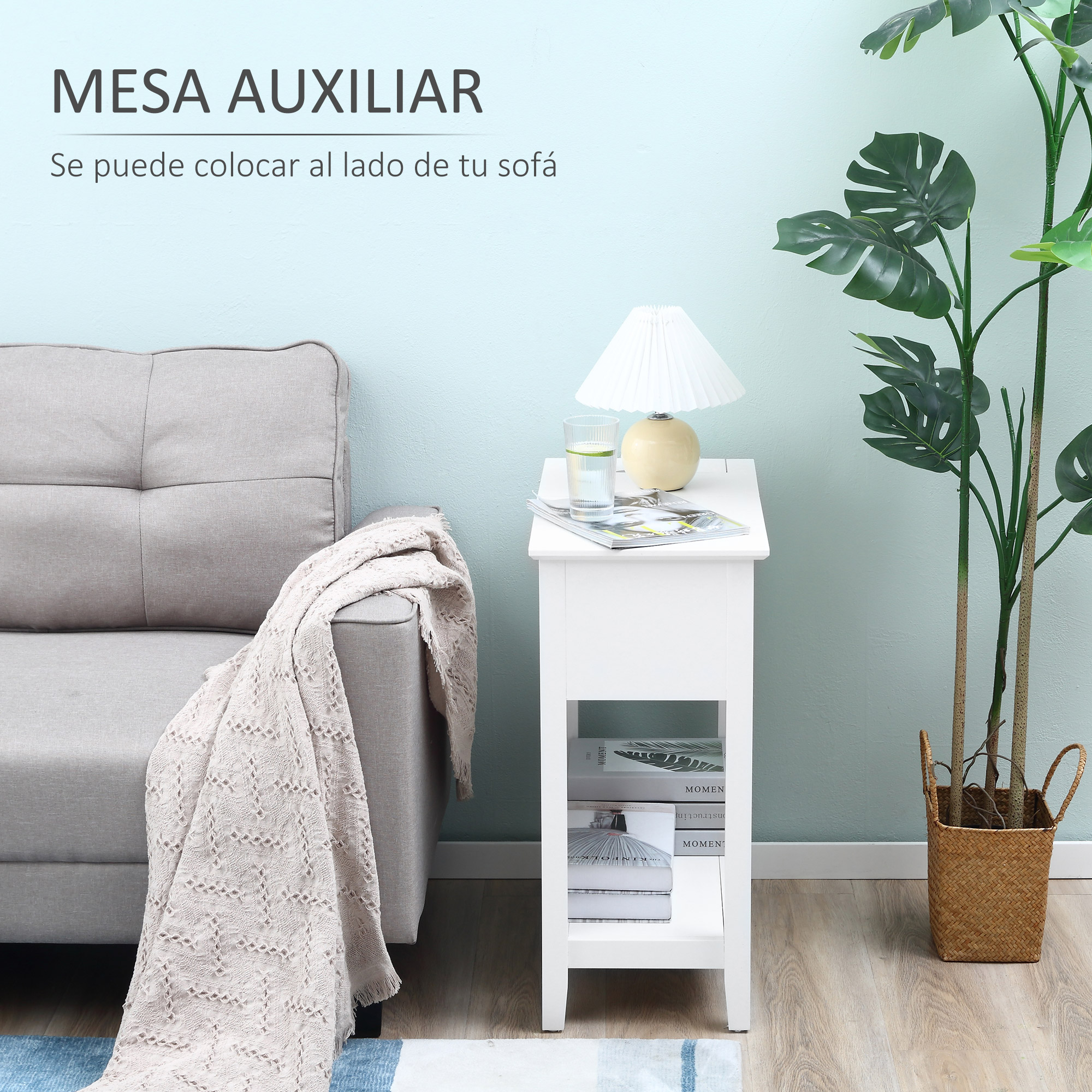 Una mesa auxiliar blanca junto a un sofá gris con una manta. Una lámpara y una planta están sobre la mesa. La pared es turquesa.