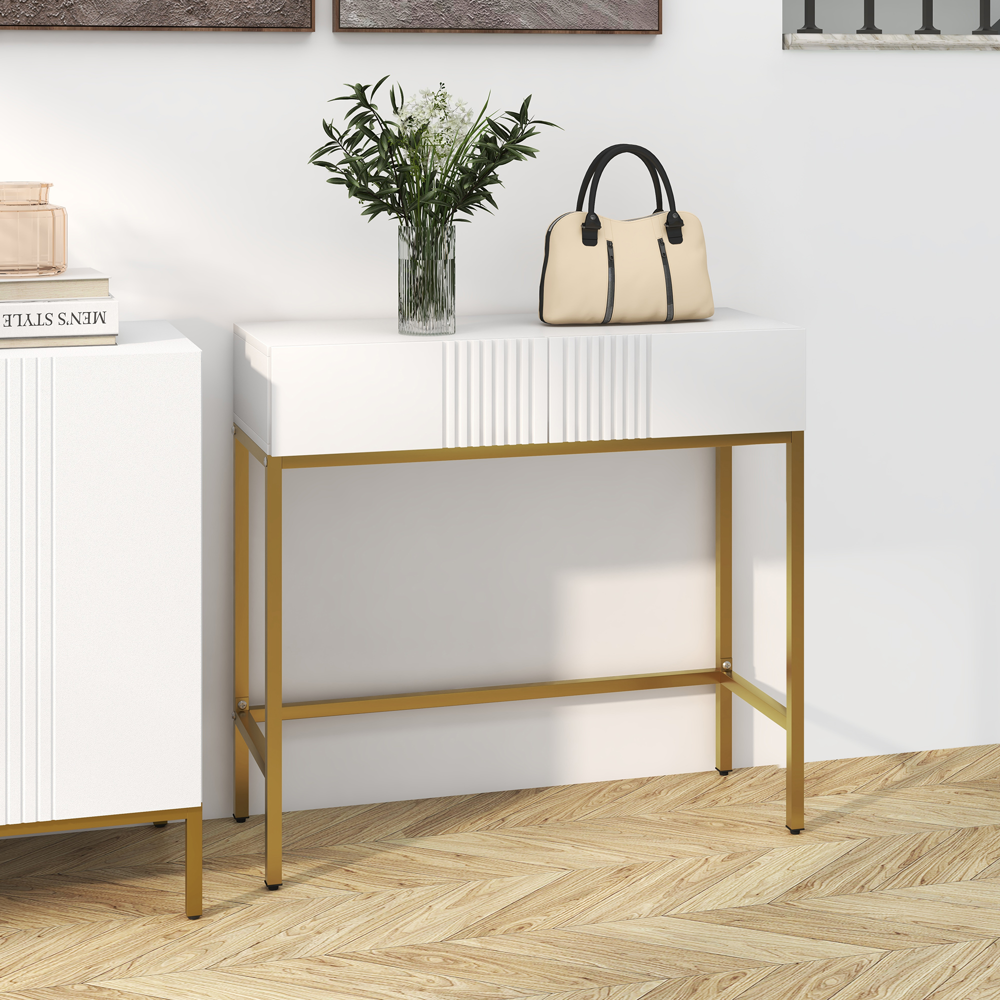 Una mesa blanca con patas doradas sostiene un bolso beige, un jarrón con flores. Libros sobre un armario blanco.
