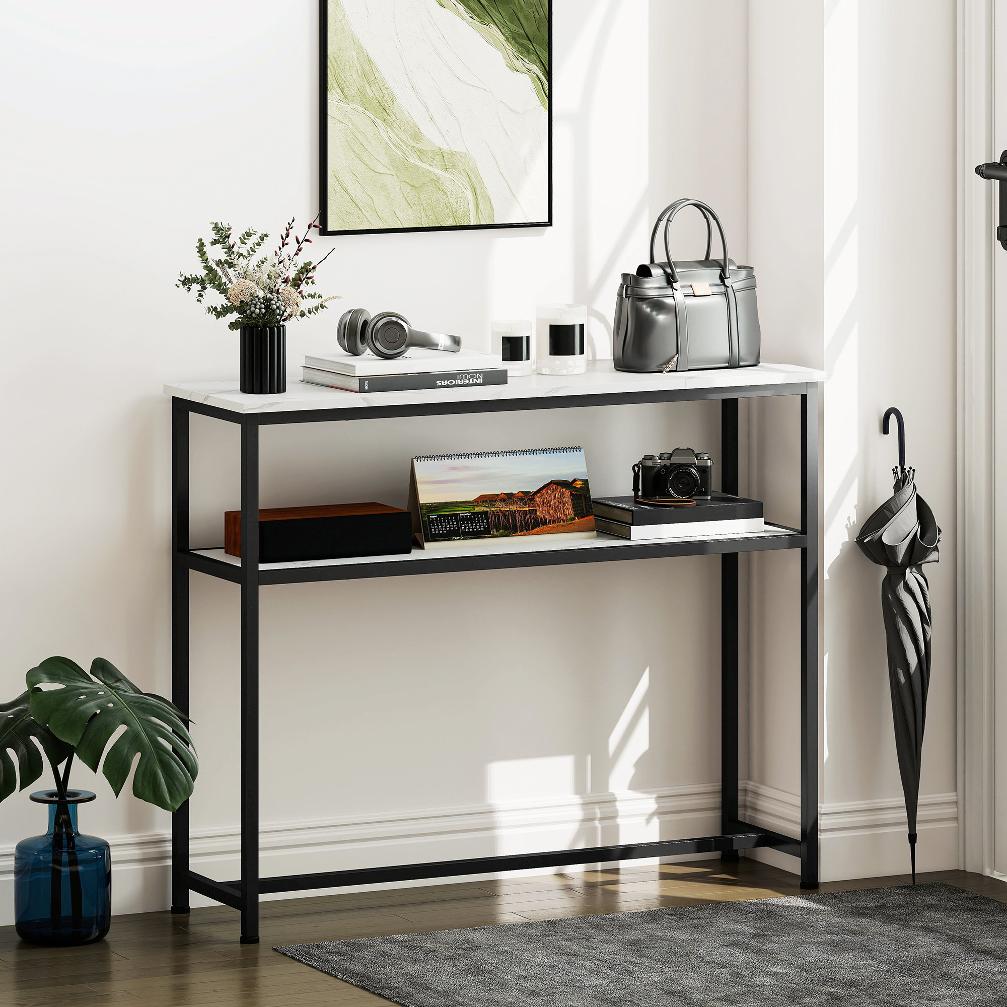 Una mesa de recibidor con decoración, incluyendo una bolsa, auriculares, flores y una cámara. Un paraguas se apoya en la pared.