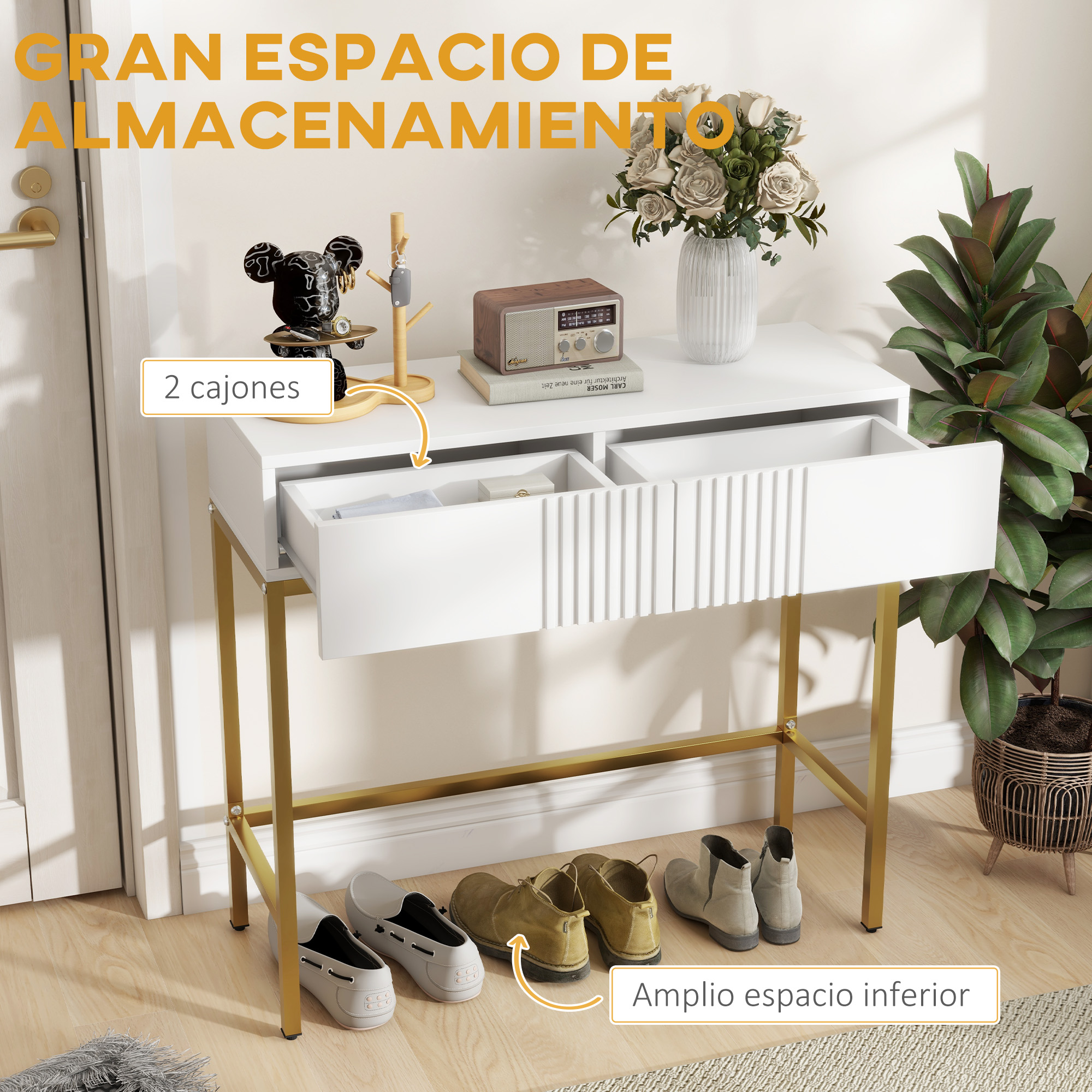 Una mesa de almacenamiento blanca con dos cajones, patas doradas y un estante para zapatos. Tiene un jarrón con flores y una planta.