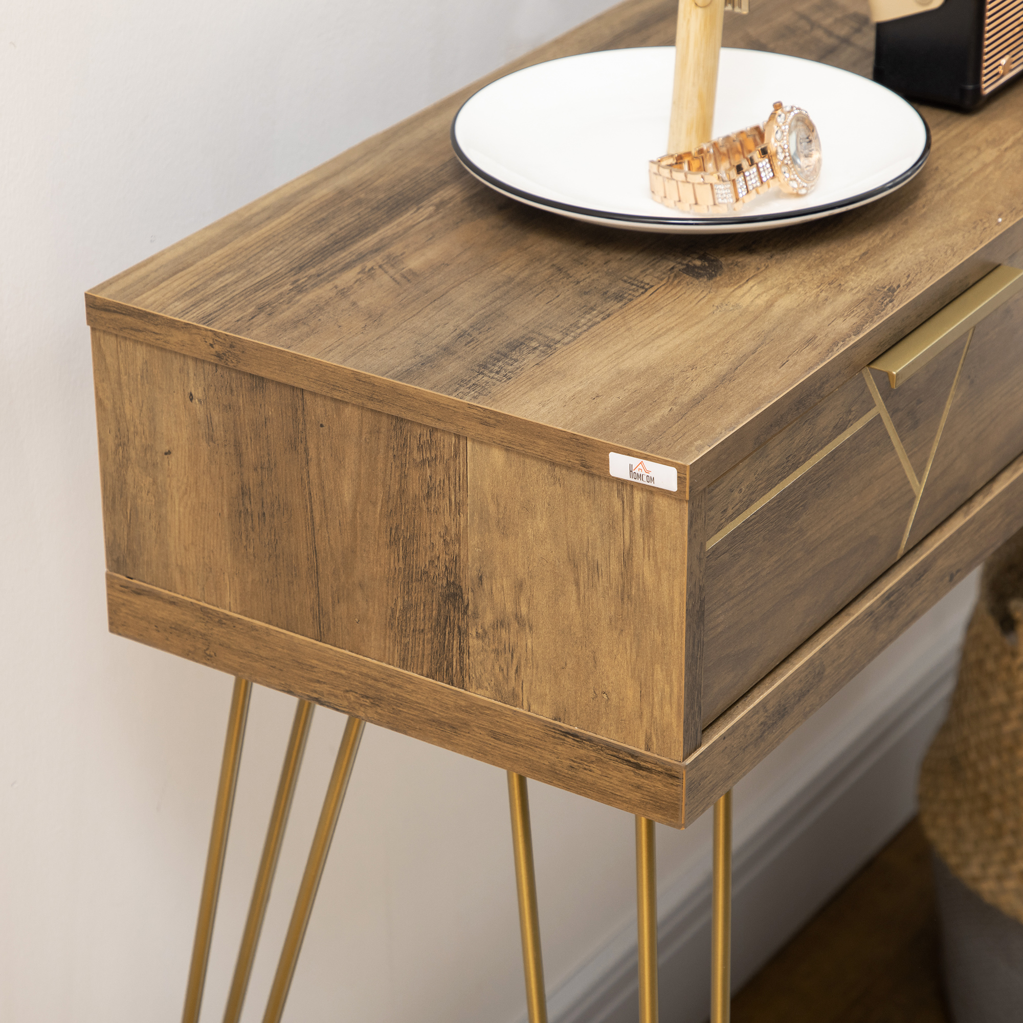Una mesa de madera con patas doradas. Encima hay un plato blanco con un reloj. Una cesta está en el fondo.