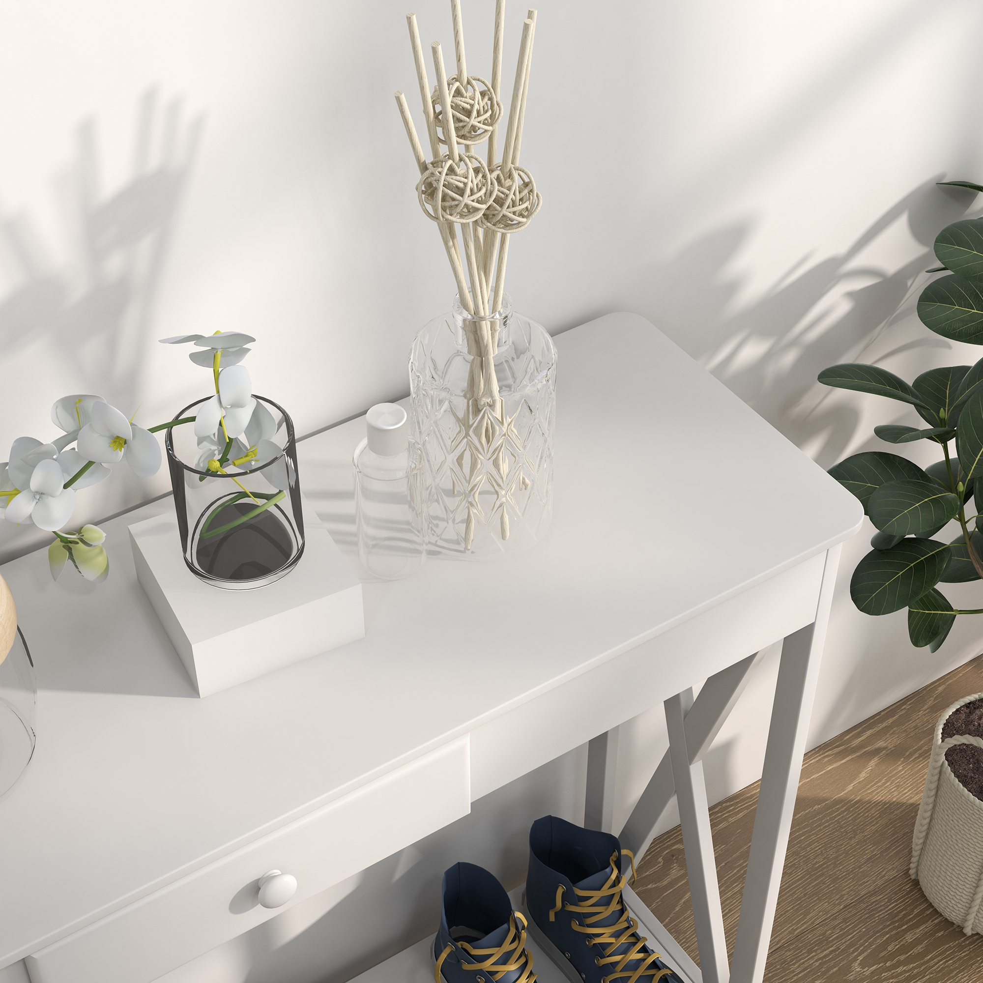 Una mesa blanca con decoraciones: una flor en un vaso, un difusor y un par de zapatillas azules con cordones amarillos.
