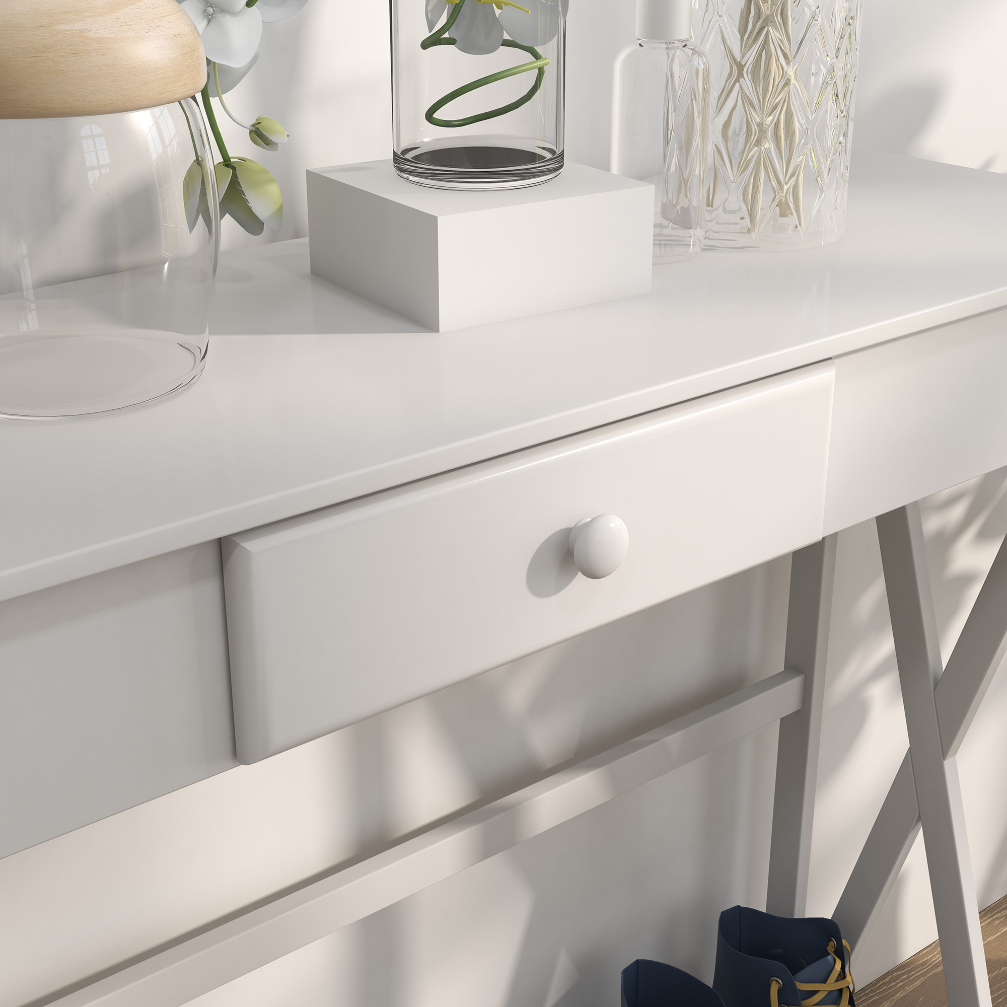Mesa blanca con cajón, jarrones y flores. Zapatos azules debajo de la mesa.