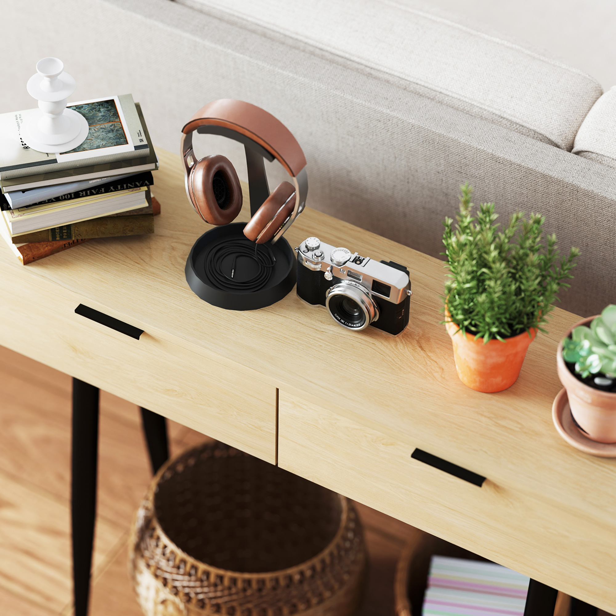 Una mesa con auriculares, cámara, libros y plantas. La escena es interior. La mesa es de madera clara.