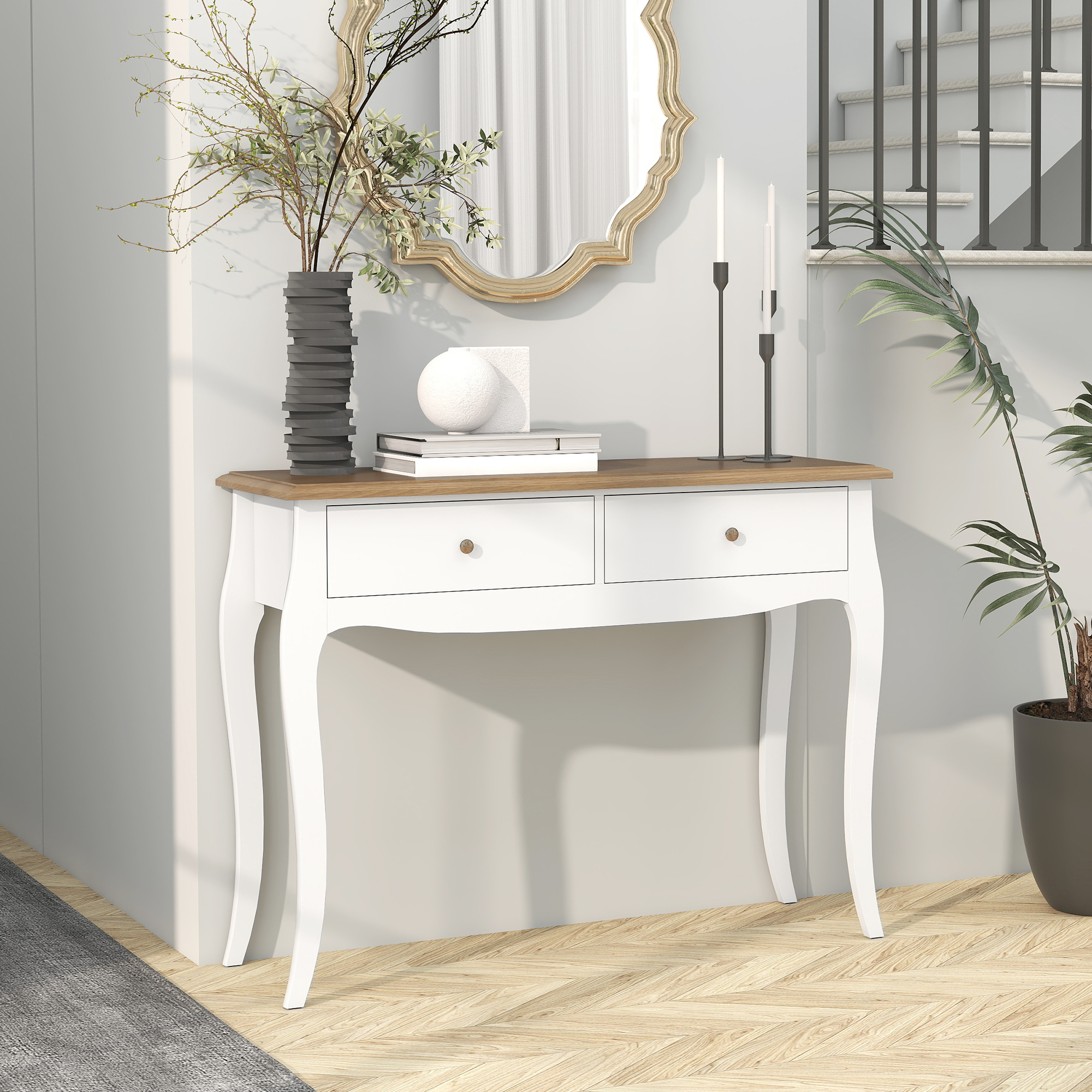 Una consola blanca con tapa de madera, espejo, velas y una planta. Una escalera visible al fondo.