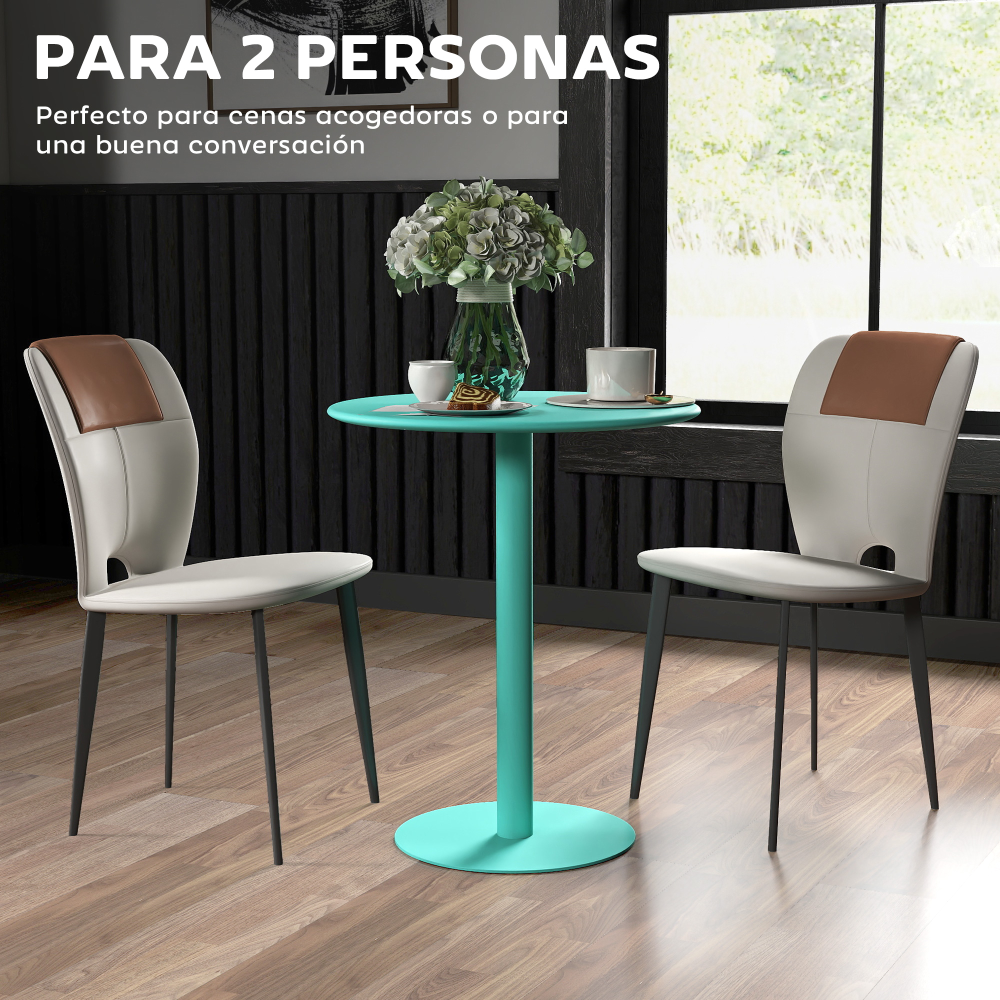 Dos sillas frente a una pequeña mesa con flores y tazas. Una ventana en el fondo.