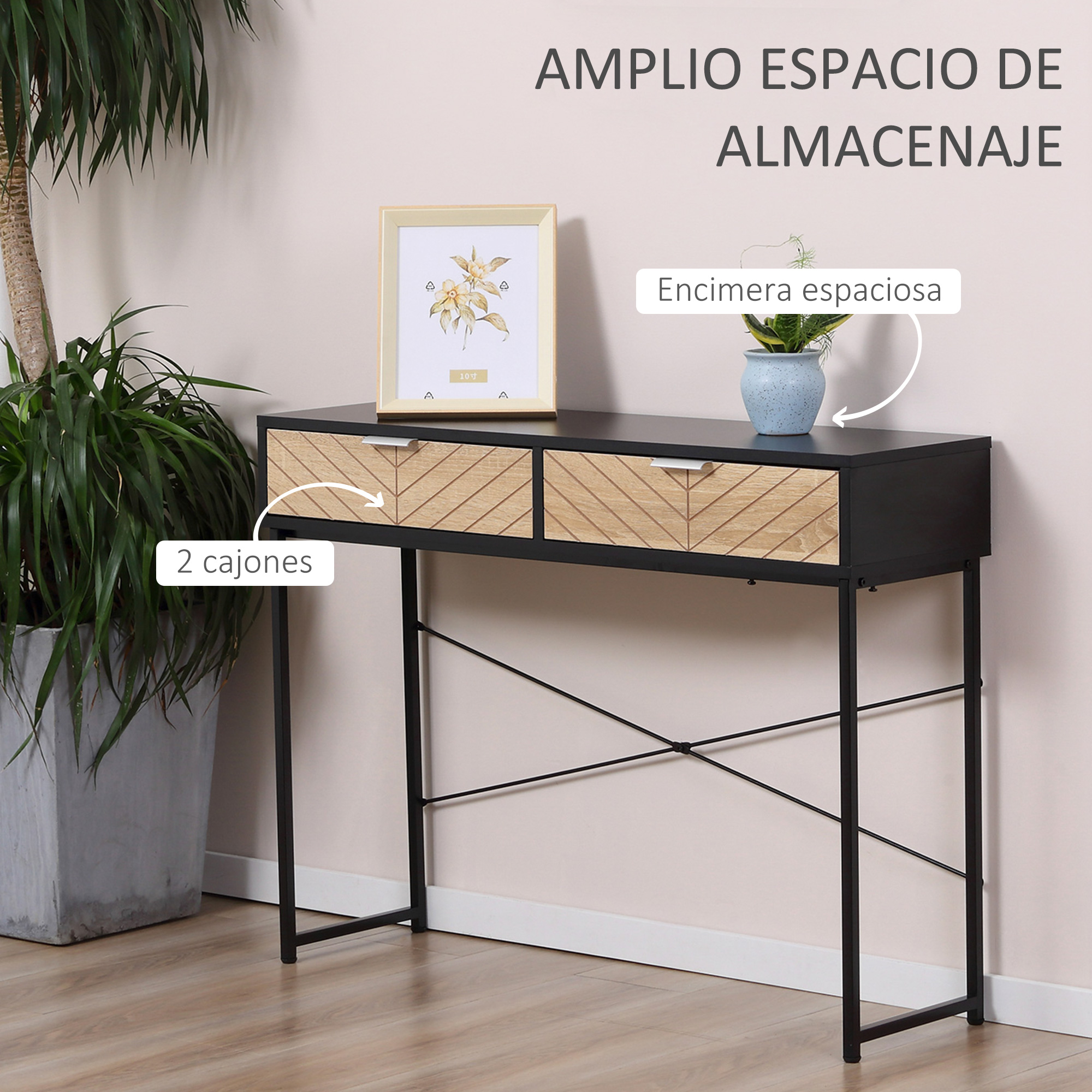 Una mesa negra con dos cajones y marco negro. Hay una maceta y un cuadro en la mesa. A la izquierda, una planta grande.