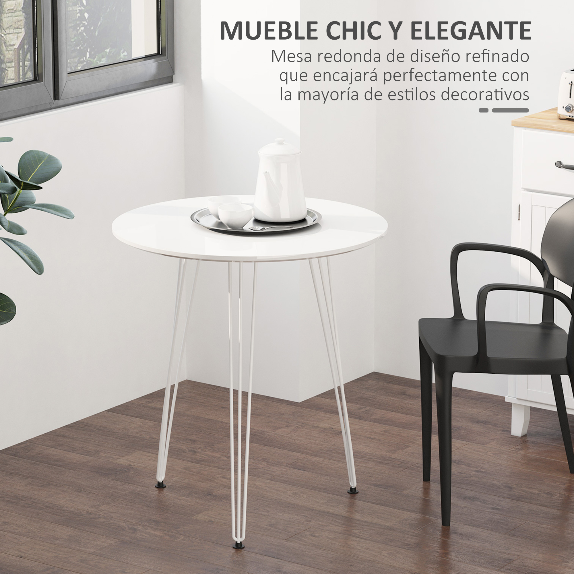 Una mesa redonda blanca con patas delgadas, una silla negra y un armario blanco contra una pared blanca y una ventana.