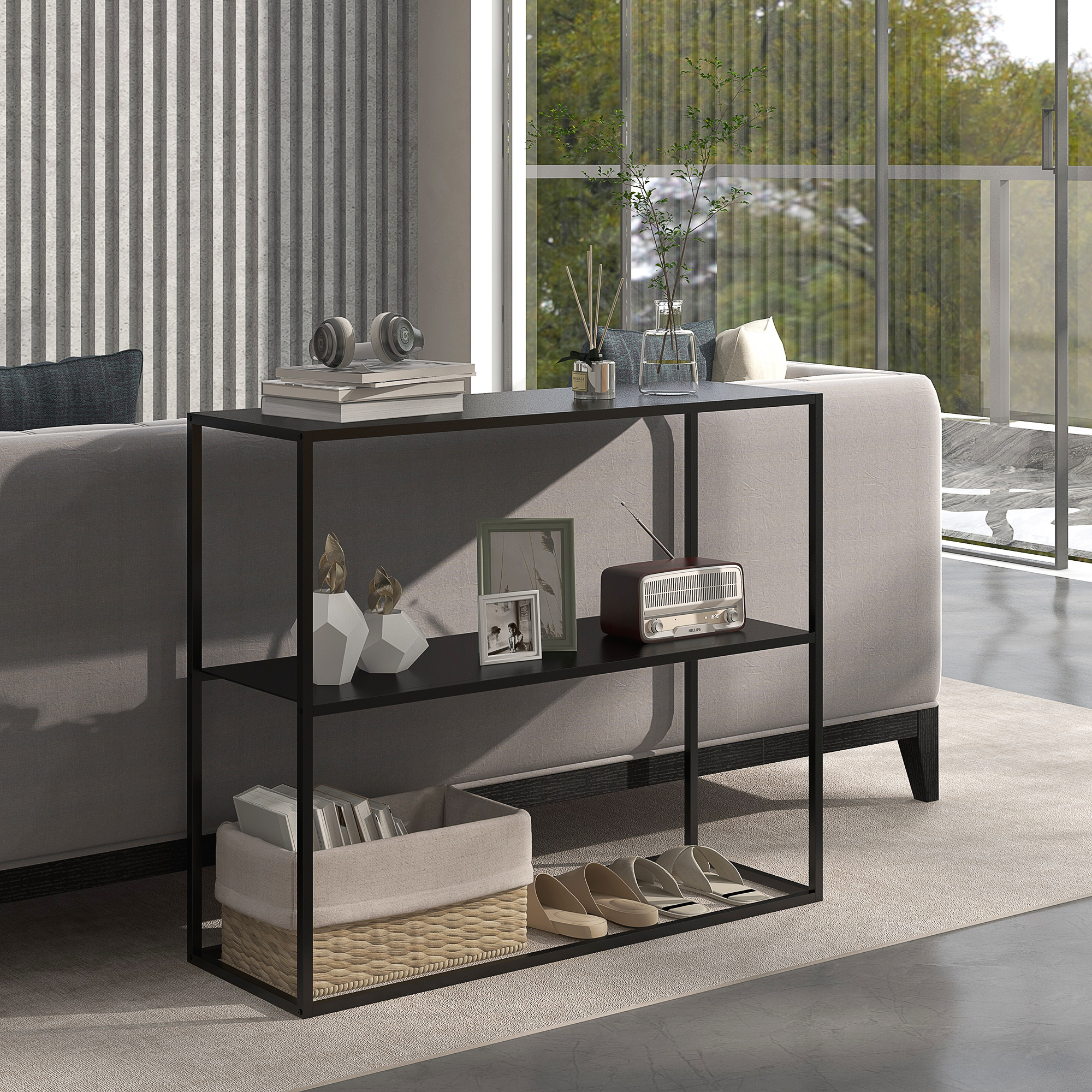 Un salón moderno con una estantería negra que contiene libros, decoración y zapatos. Un sofá gris y una ventana al fondo.