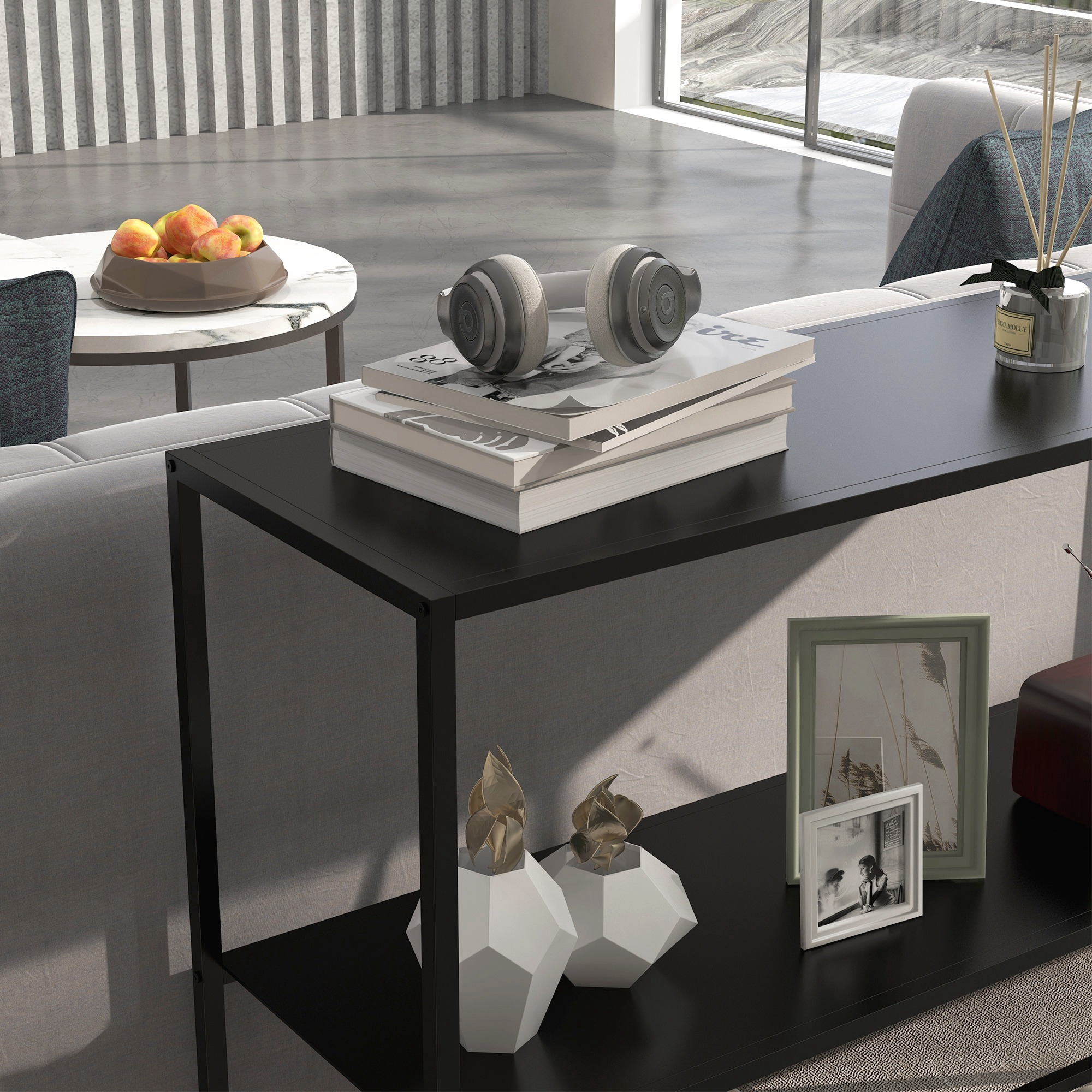 Un salón moderno con una mesa negra. Hay auriculares, libros, decoración y fruta en la mesa. Un sofá está en el fondo.