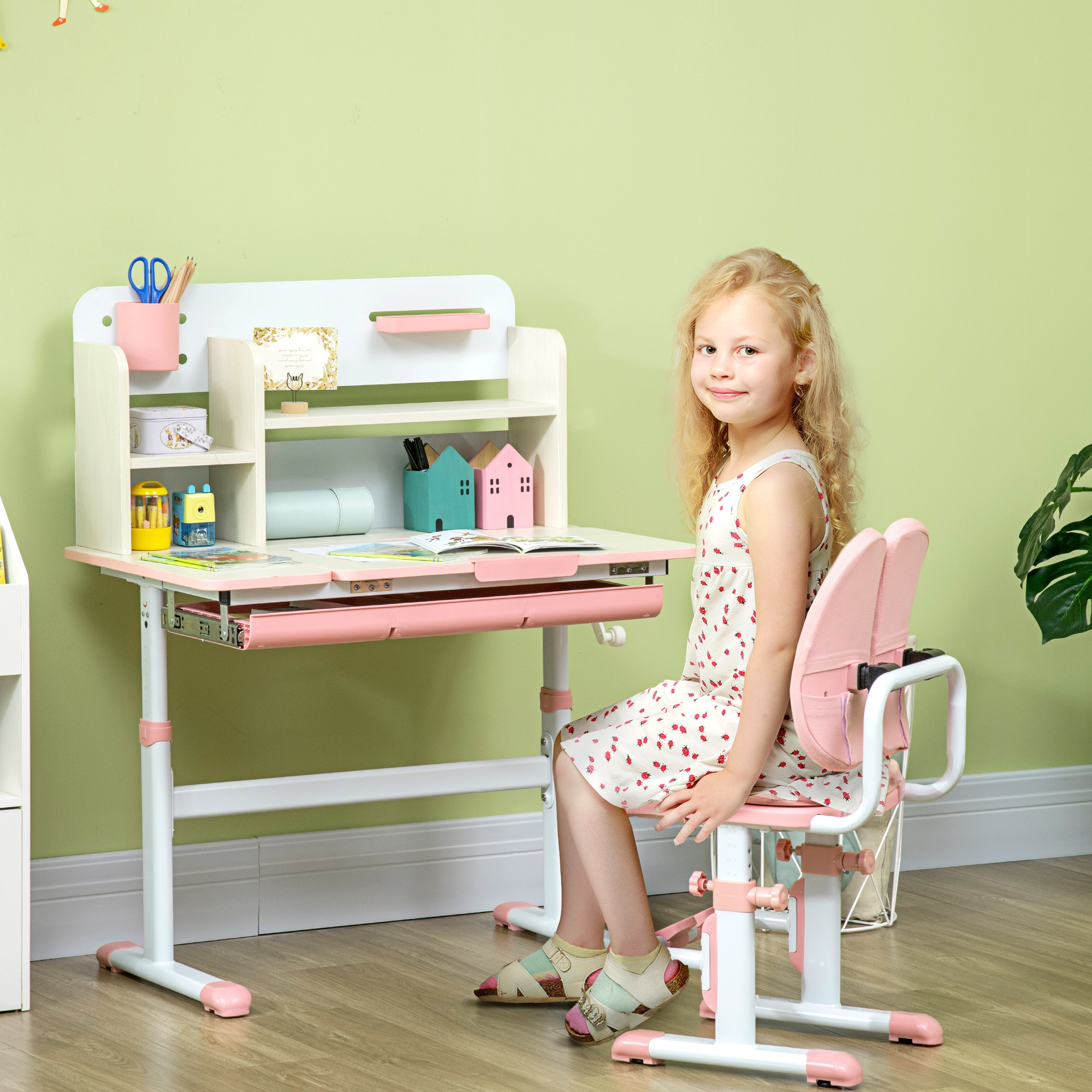 Una niña sonríe sentada en un escritorio rosa. El escritorio tiene una tapa blanca y un cajón rosa. Hay una silla rosa.