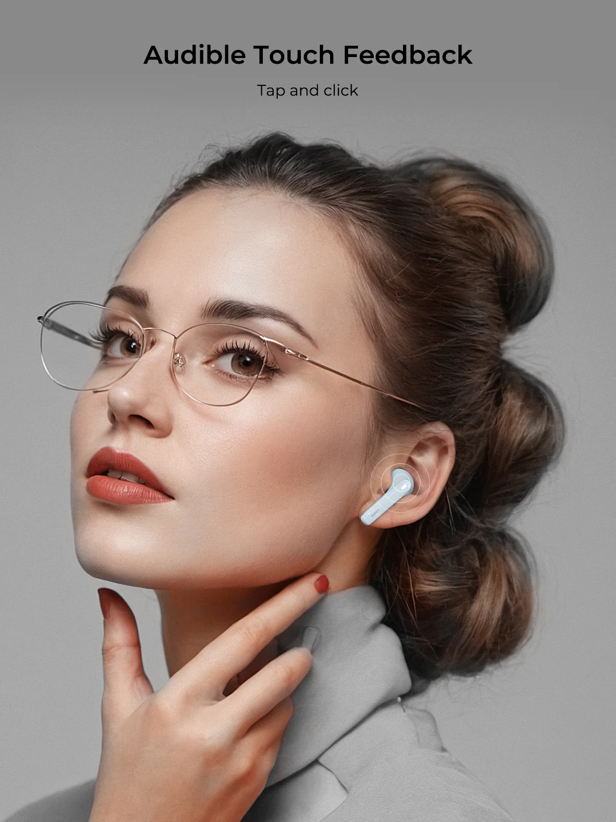 Una mujer con gafas y un auricular se toca el cuello. Fondo gris, texto arriba: 'Audible Touch Feedback'.