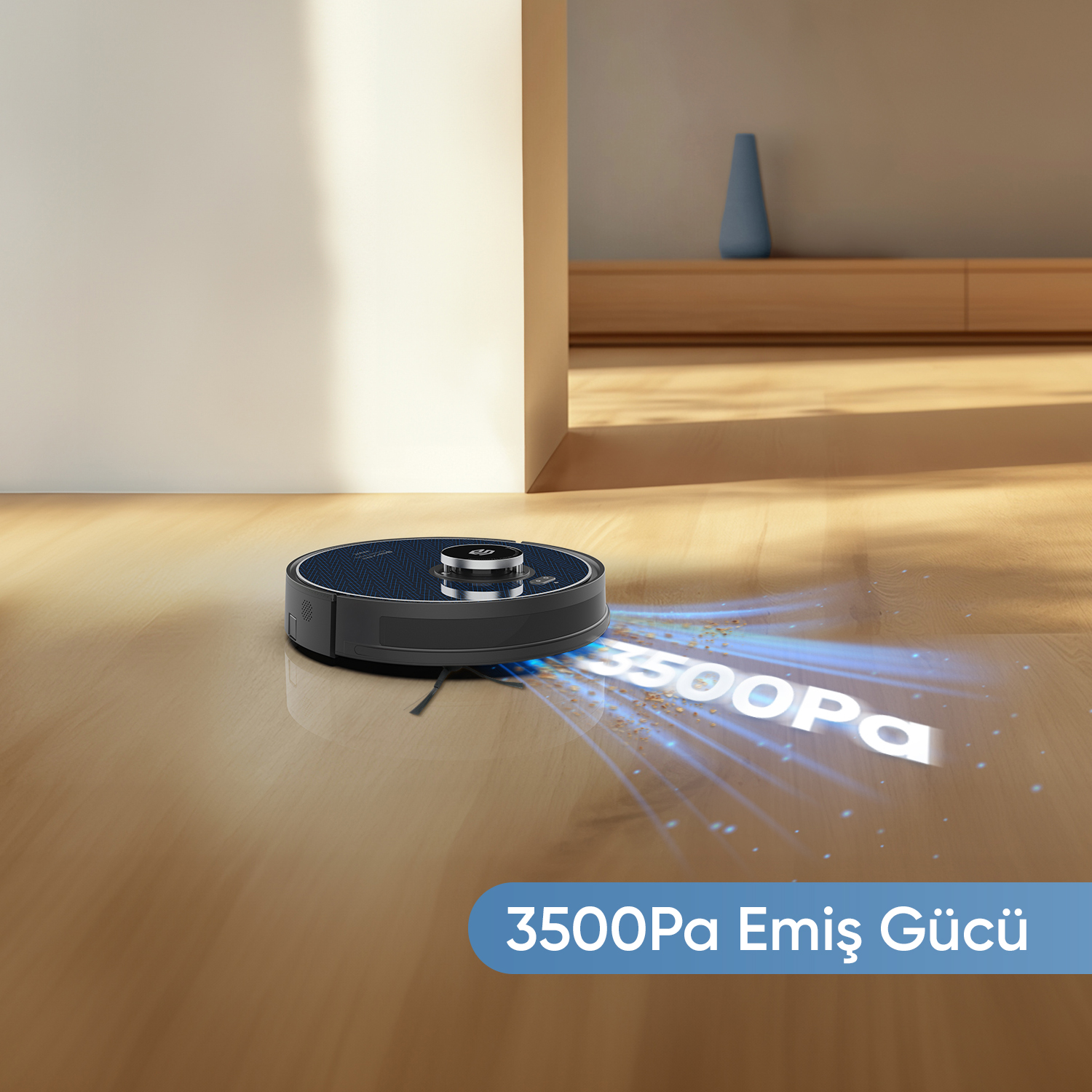 Ahşap zeminde bir robot süpürge. Zemindeki metin '3500Pa' yazıyor. Rafta mavi bir vazo var.