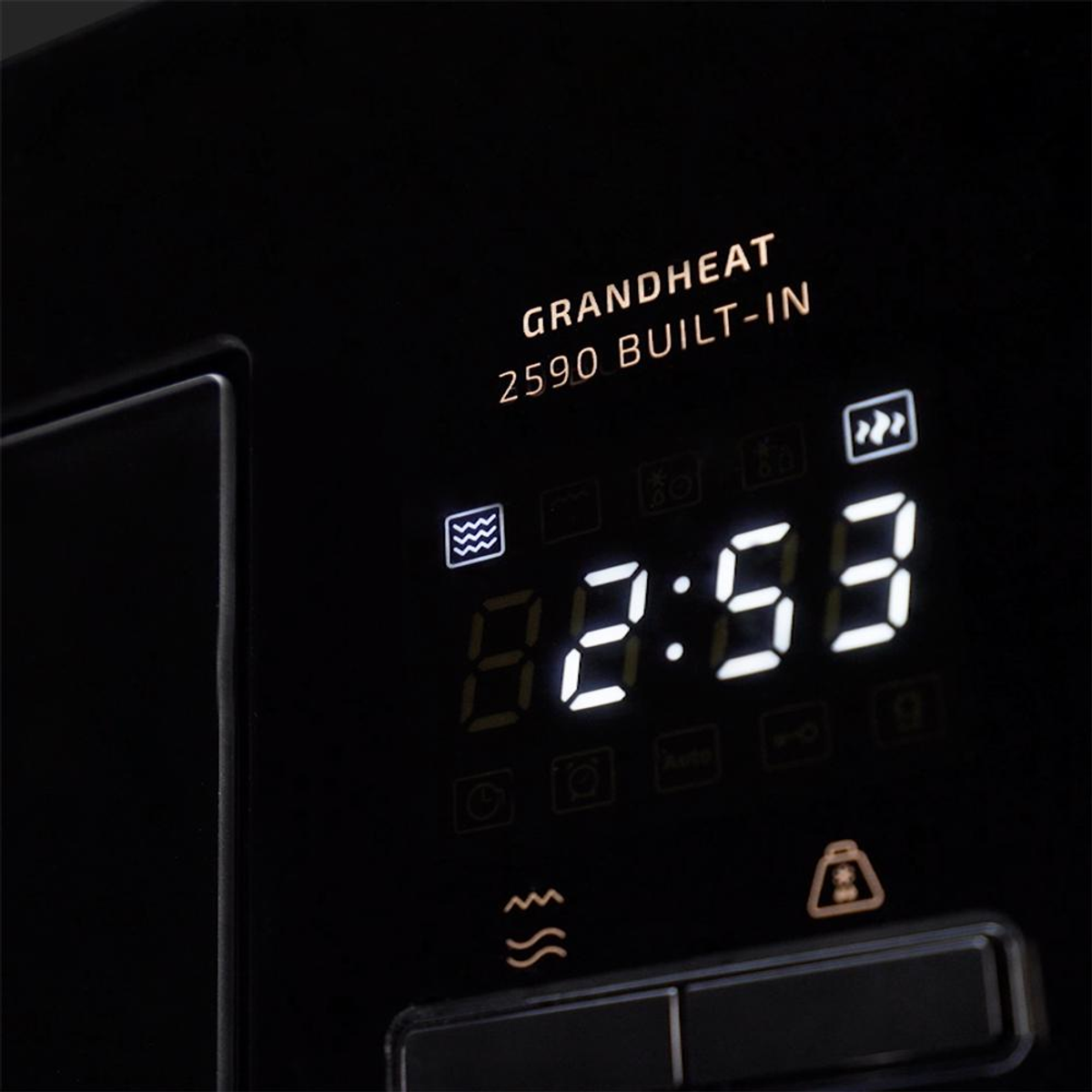 Zbliżenie wyświetlacza kuchenki mikrofalowej. Pokazuje godzinę 8:53. Piekarnik jest czarny, z białym tekstem i logo.