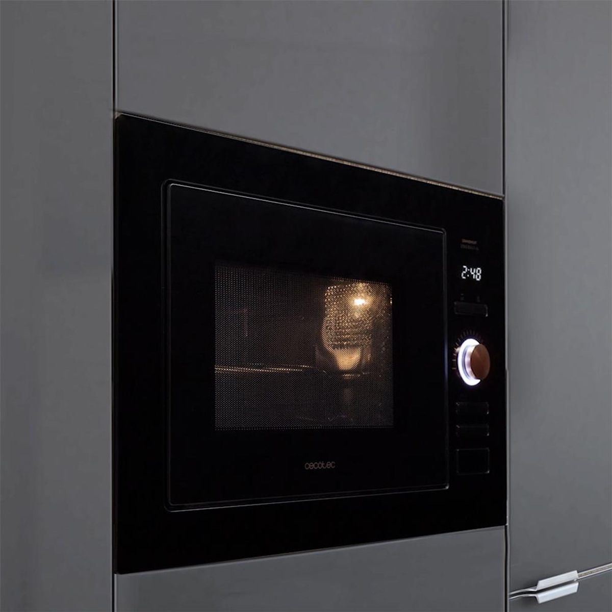 Czarna kuchenka mikrofalowa jest wbudowana w szarą szafkę. Wnętrze piekarnika jest podświetlone i pokazuje godzinę 2:48. Marka: Cecotec.