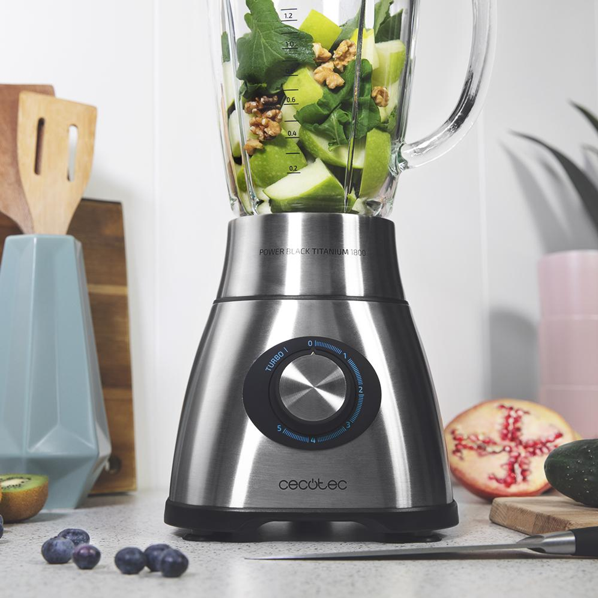 Una licuadora con frutas y nueces. Arándanos, kiwi y granada están en el mostrador.