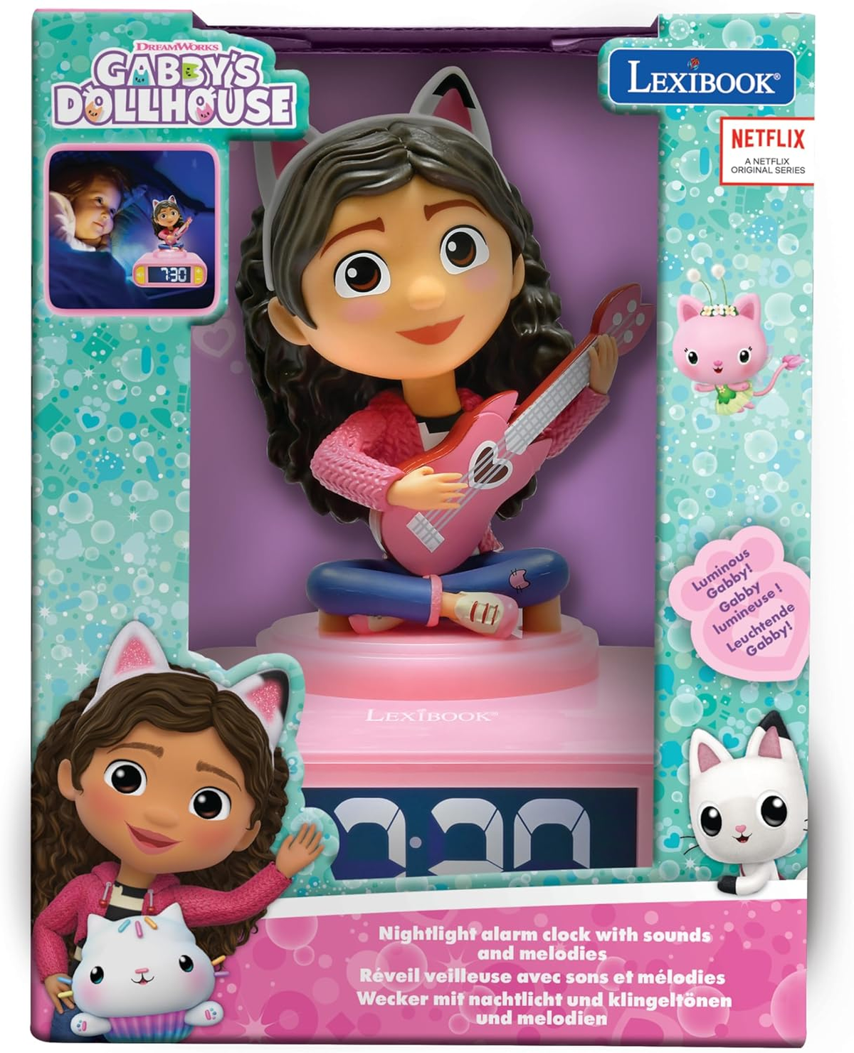 Un juguete de despertador con luz nocturna de Gabby's Dollhouse. La figura de Gabby toca la guitarra. El embalaje muestra el juguete y los personajes.