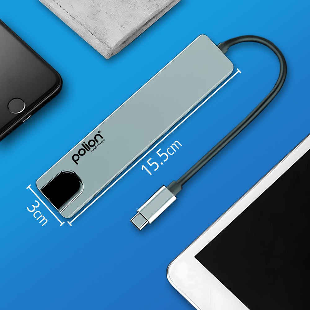 Szary hub USB-C Polion z czarnym kablem. Ma 15,5 cm długości i 3 cm szerokości, ze smartfonem i tabletem na niebieskiej powierzchni.