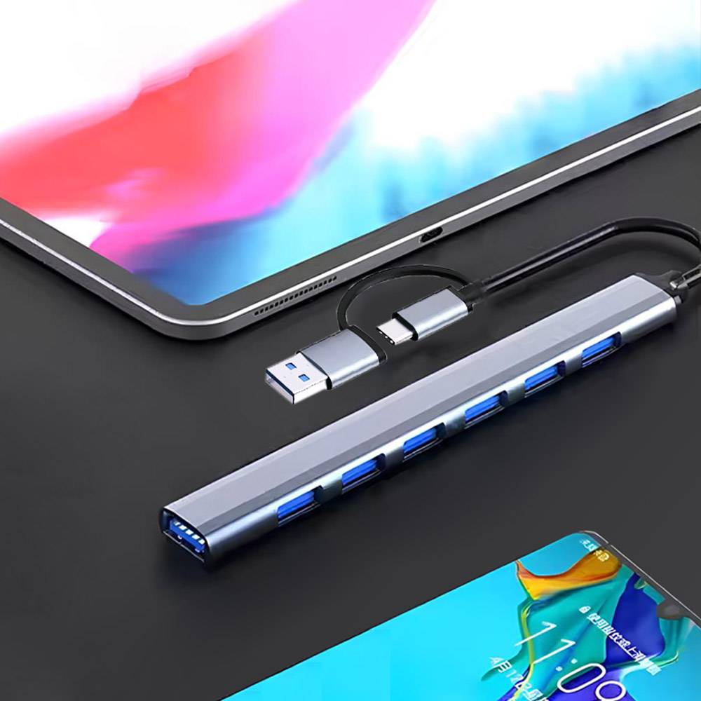 Srebrny hub USB z niebieskimi portami jest podłączony do tabletu i telefonu. Hub ma złącza USB-A i USB-C.