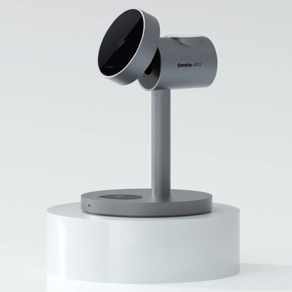 Un dispositivo de carga gris con el nombre 'Omnia-Blitz' y 'AUKEY' sobre un pedestal blanco.