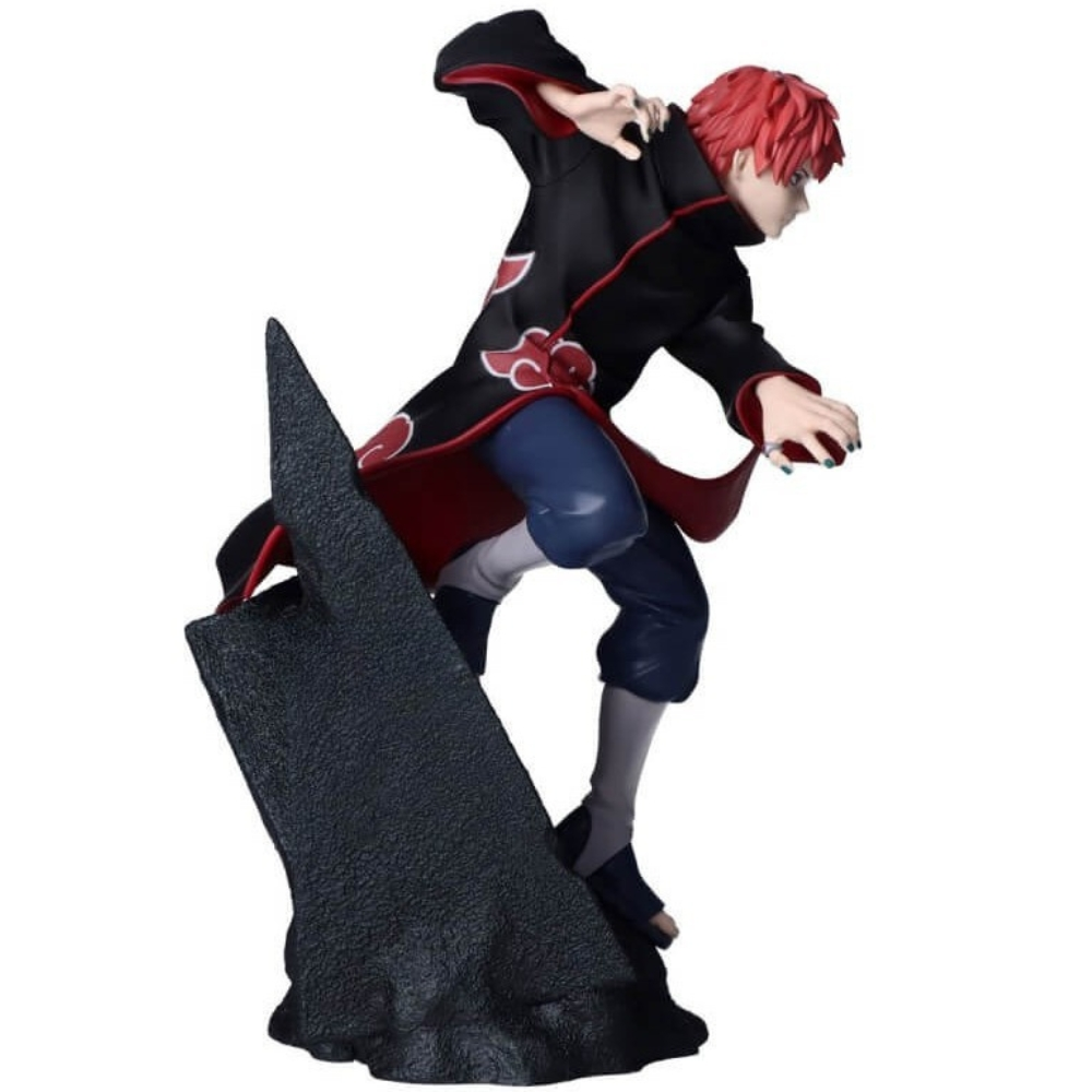 Una statuetta di un personaggio con capelli rossi, cappotto nero con fodera rossa e simboli di nuvole, pantaloni blu e stivali grigi, su una base di pietra.