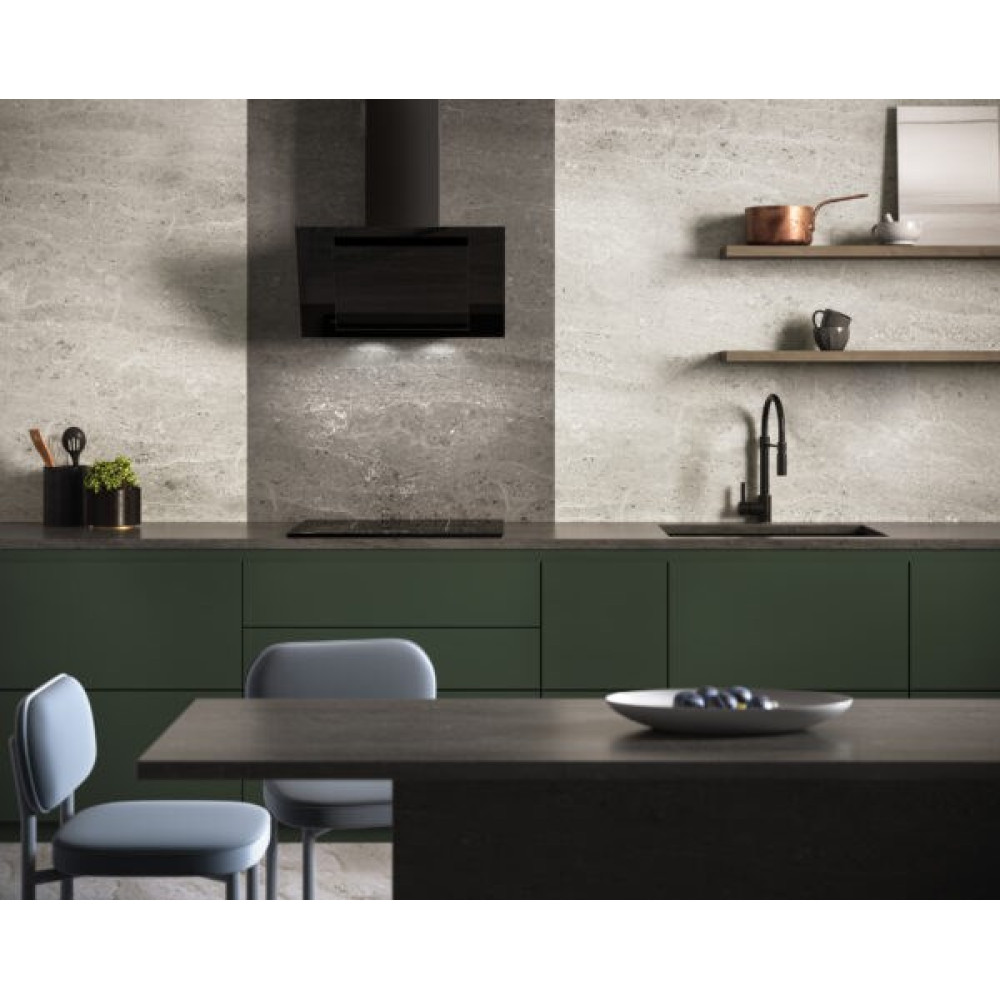 Nowoczesna kuchnia z zielonymi szafkami, czarnymi urządzeniami i stołem z krzesłami. Na stole talerz z owocami.