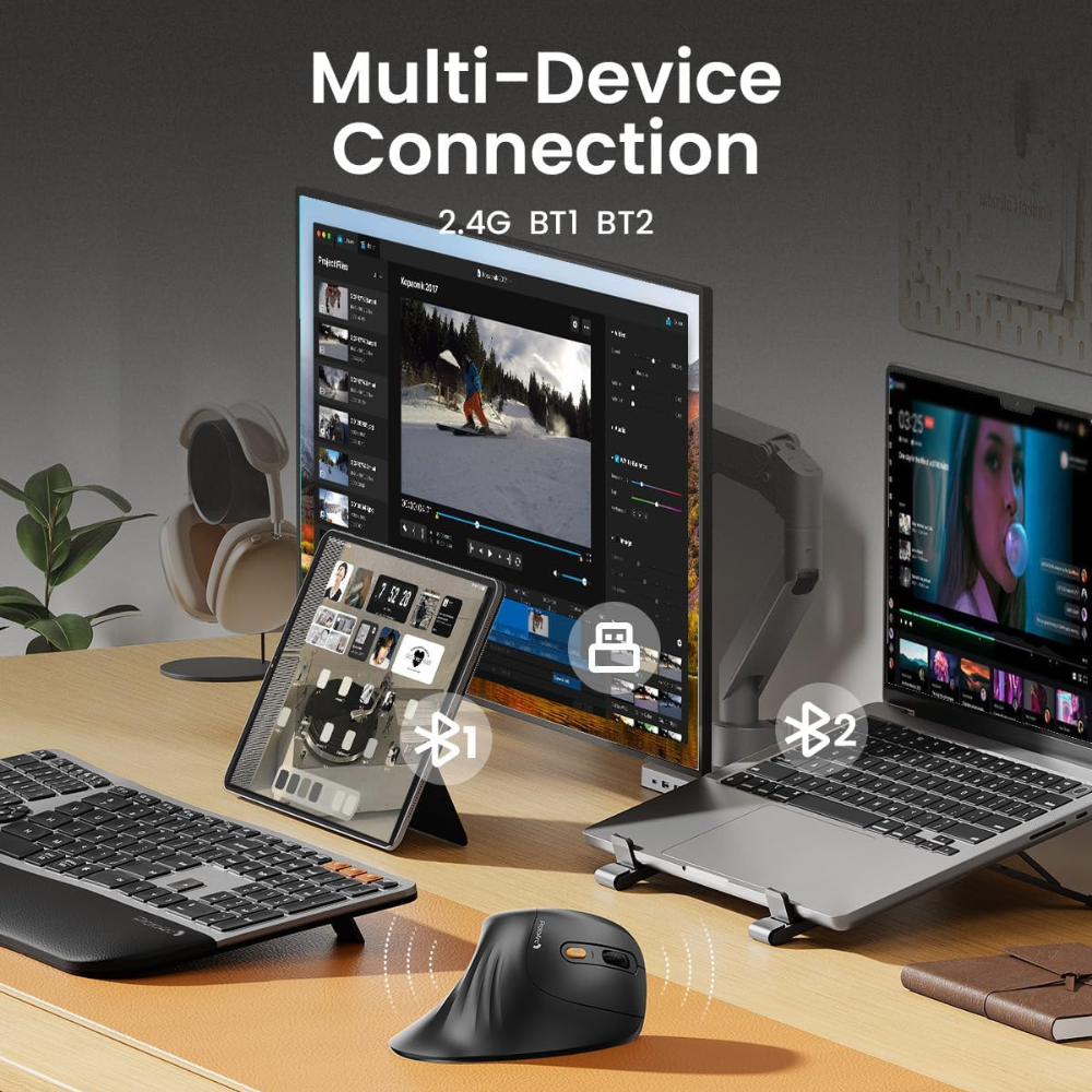 A desk setup with multiple devices. A monitor, laptop, and tablet connected wirelessly with a keyboard and mouse.