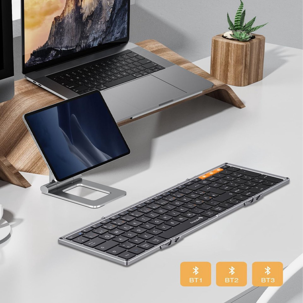 Ein Schreibtisch-Setup mit Laptop, Tablet und Tastatur. Eine Pflanze in einem Holztopf steht neben dem Laptop.