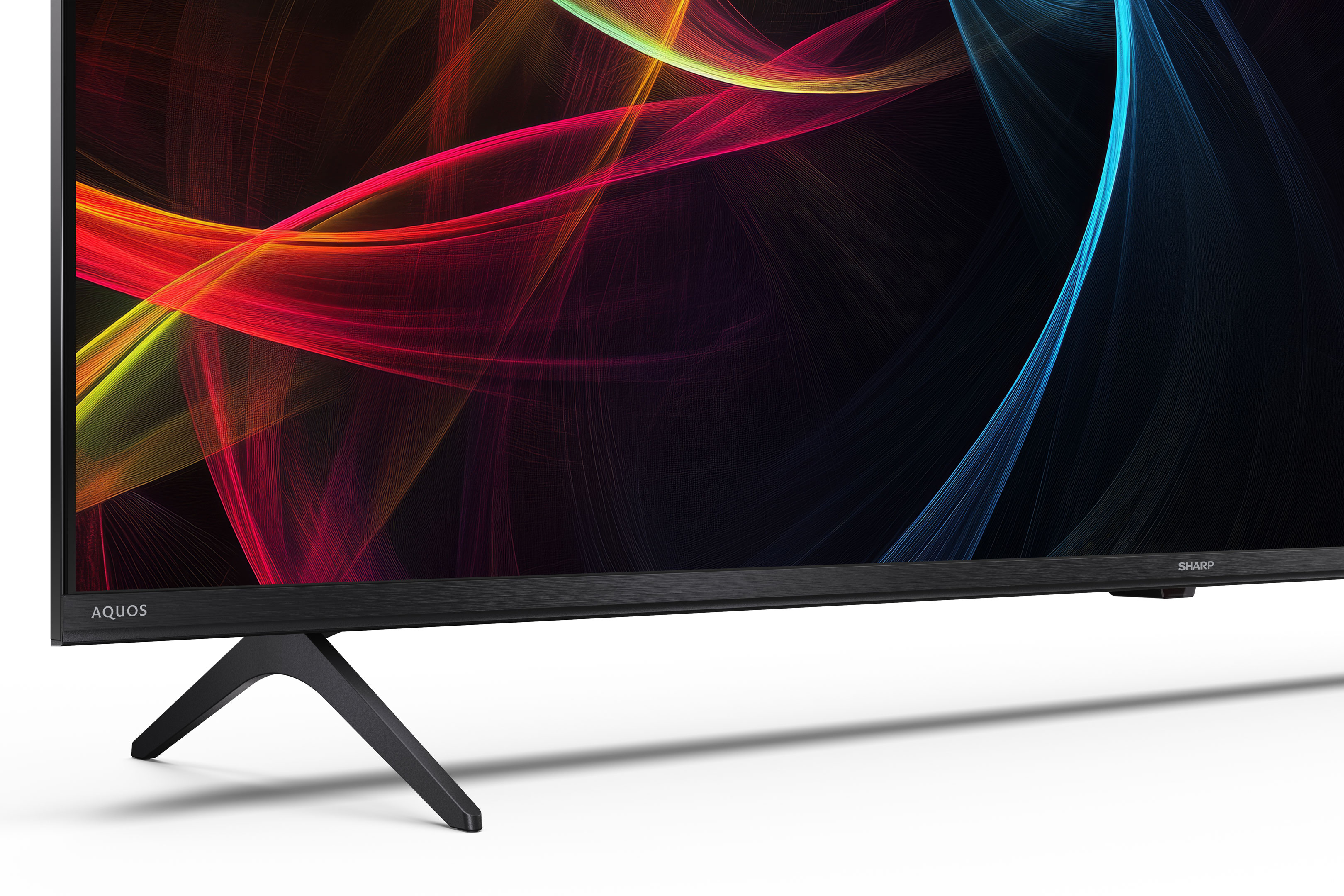 Een Sharp Aquos tv toont kleurrijke, abstracte lijnen op zwarte achtergrond, ondersteund door een zwarte standaard.