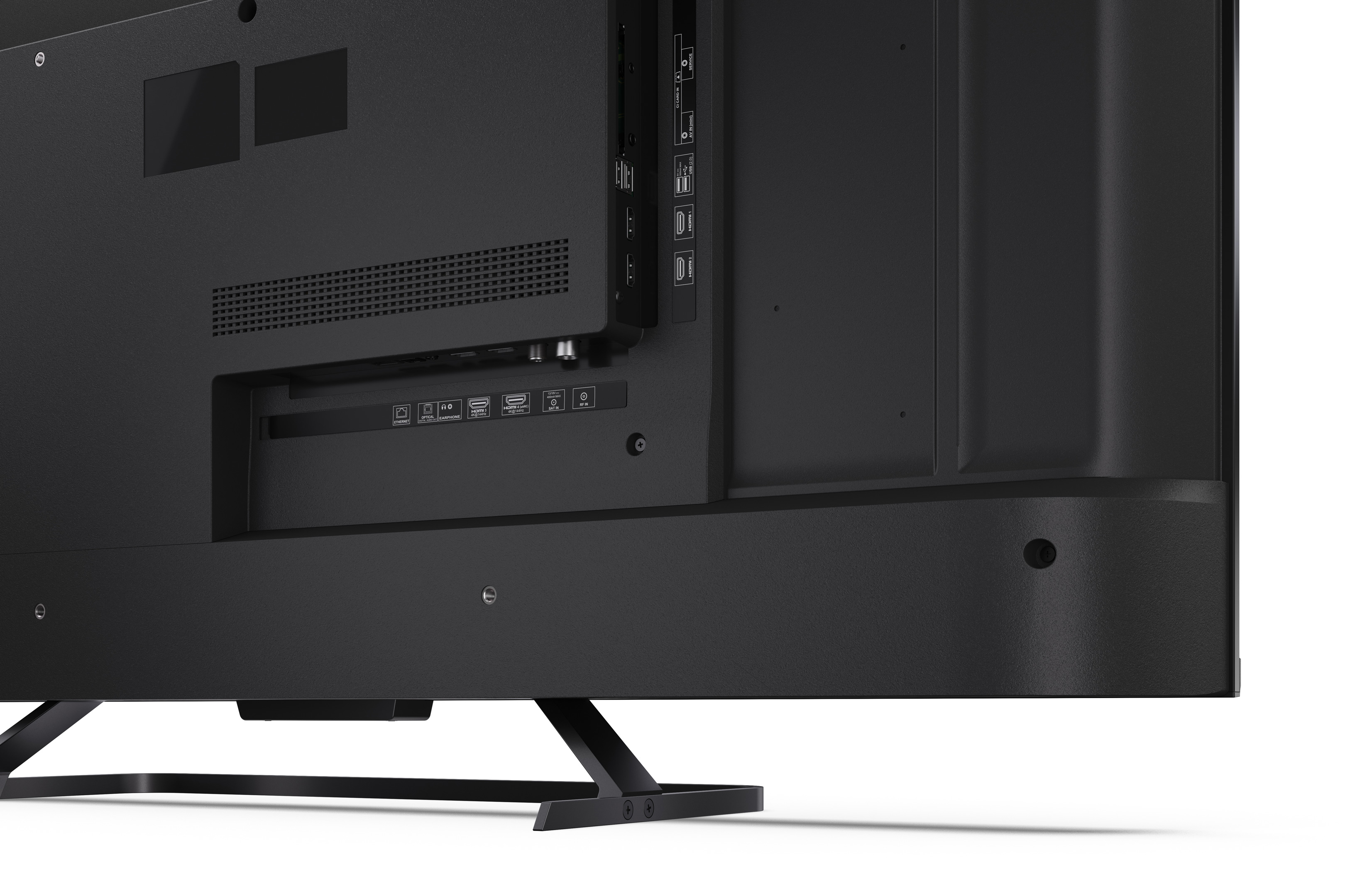 Widok z tyłu czarnego telewizora. Widoczne porty: HDMI, USB i inne. Telewizor stoi na czarnym stojaku.