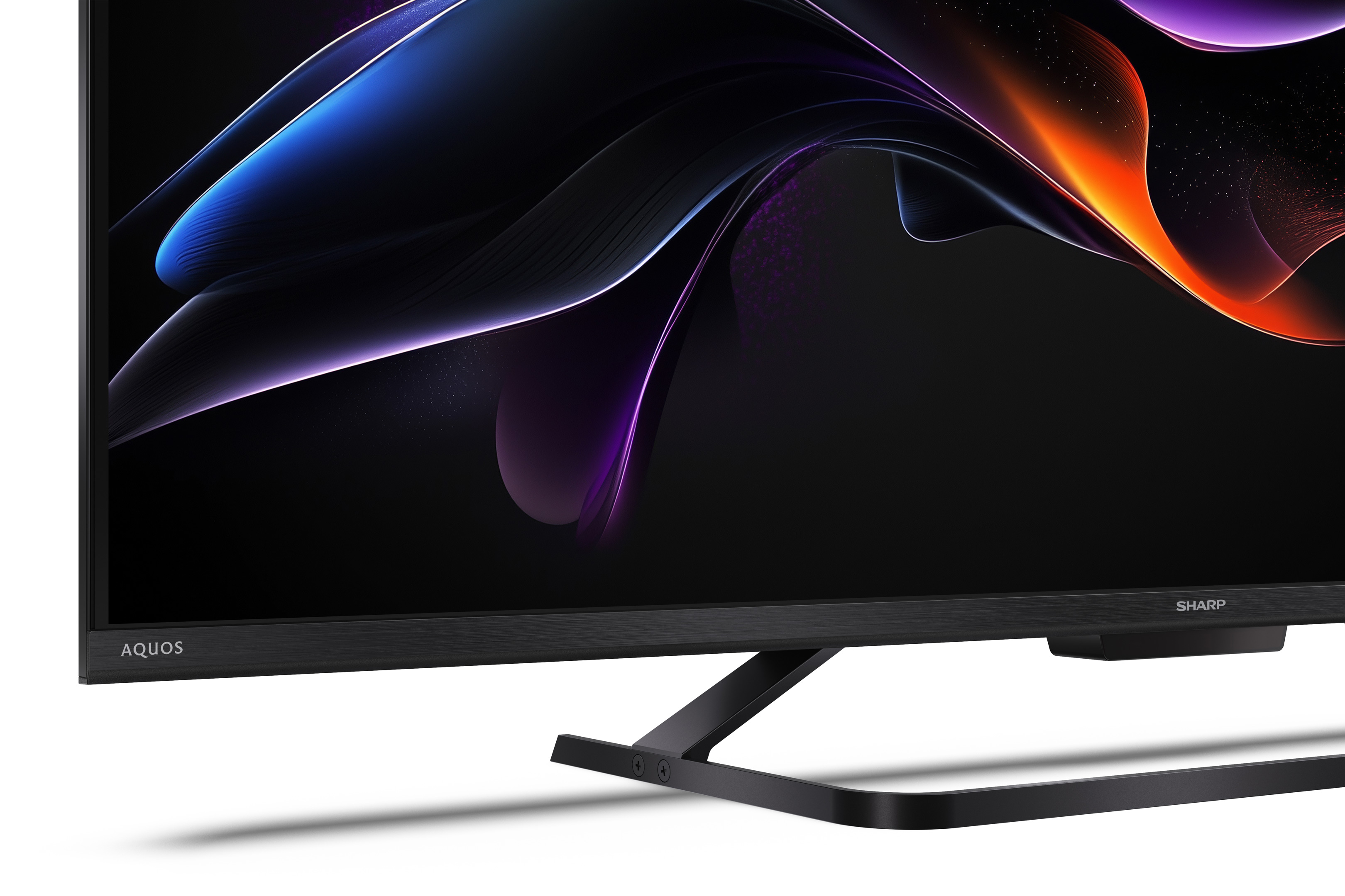 Telewizor Sharp Aquos wyświetla kolorowy, abstrakcyjny wzór. Telewizor jest czarny z czarną podstawą na białej powierzchni.