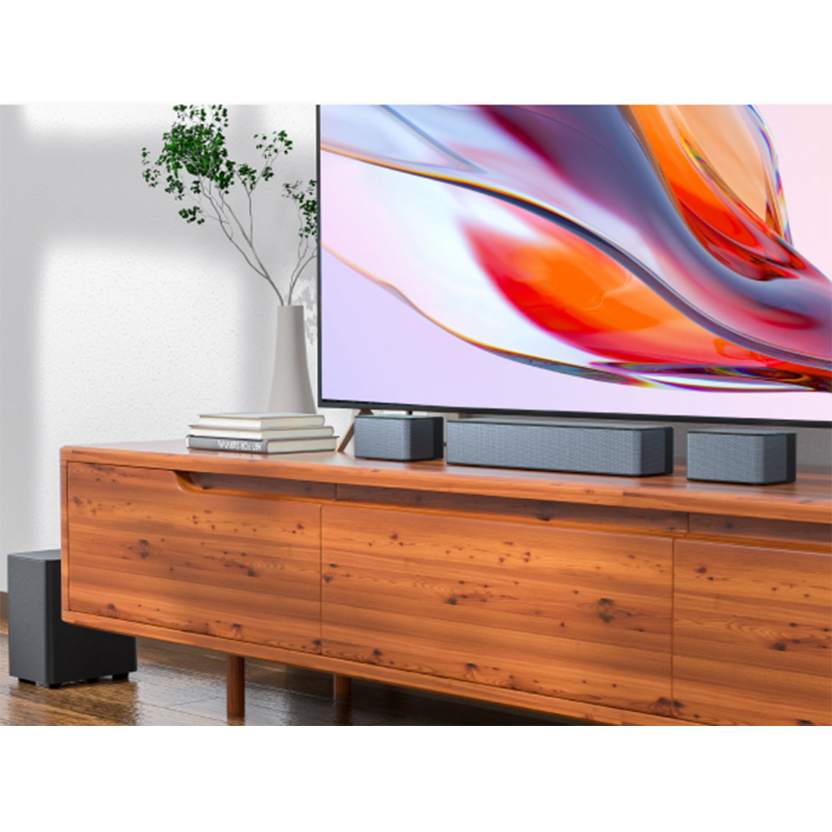 Drewniana szafka z telewizorem i głośnikami. Wazon z rośliną stoi na szafce. Mały subwoofer stoi na podłodze.