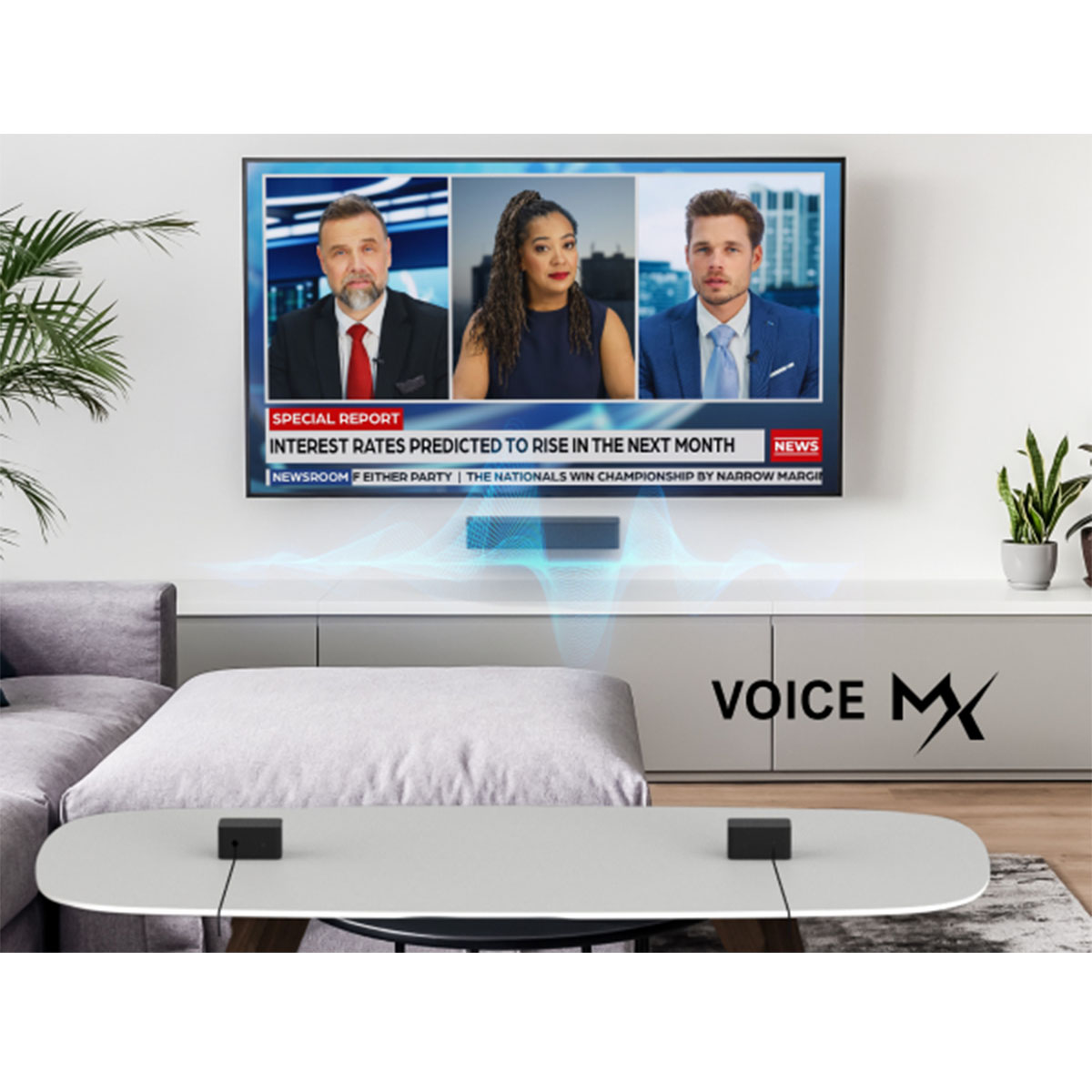 Telewizor pokazuje prezenterów wiadomości. Poniżej stół z czarnymi pudełkami. Tekst 'VOICE MX' jest po prawej.