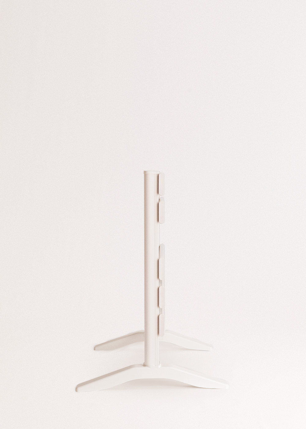 Un soporte blanco con un poste central y dos pies. El fondo es de color blanquecino liso.