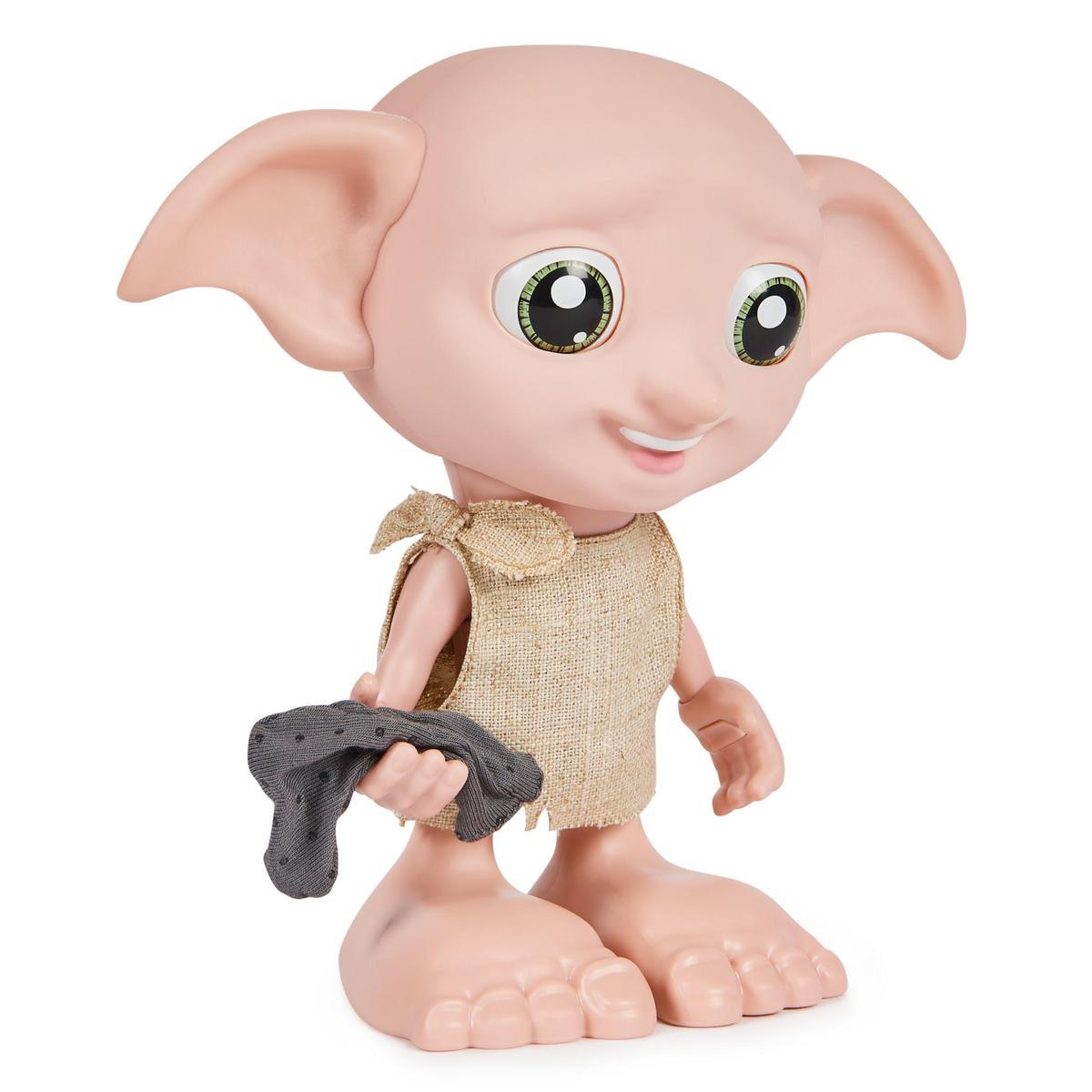 Una muñeca Dobby sostiene un calcetín gris. Tiene ojos verdes grandes, orejas grandes y está vestida con tela de saco.