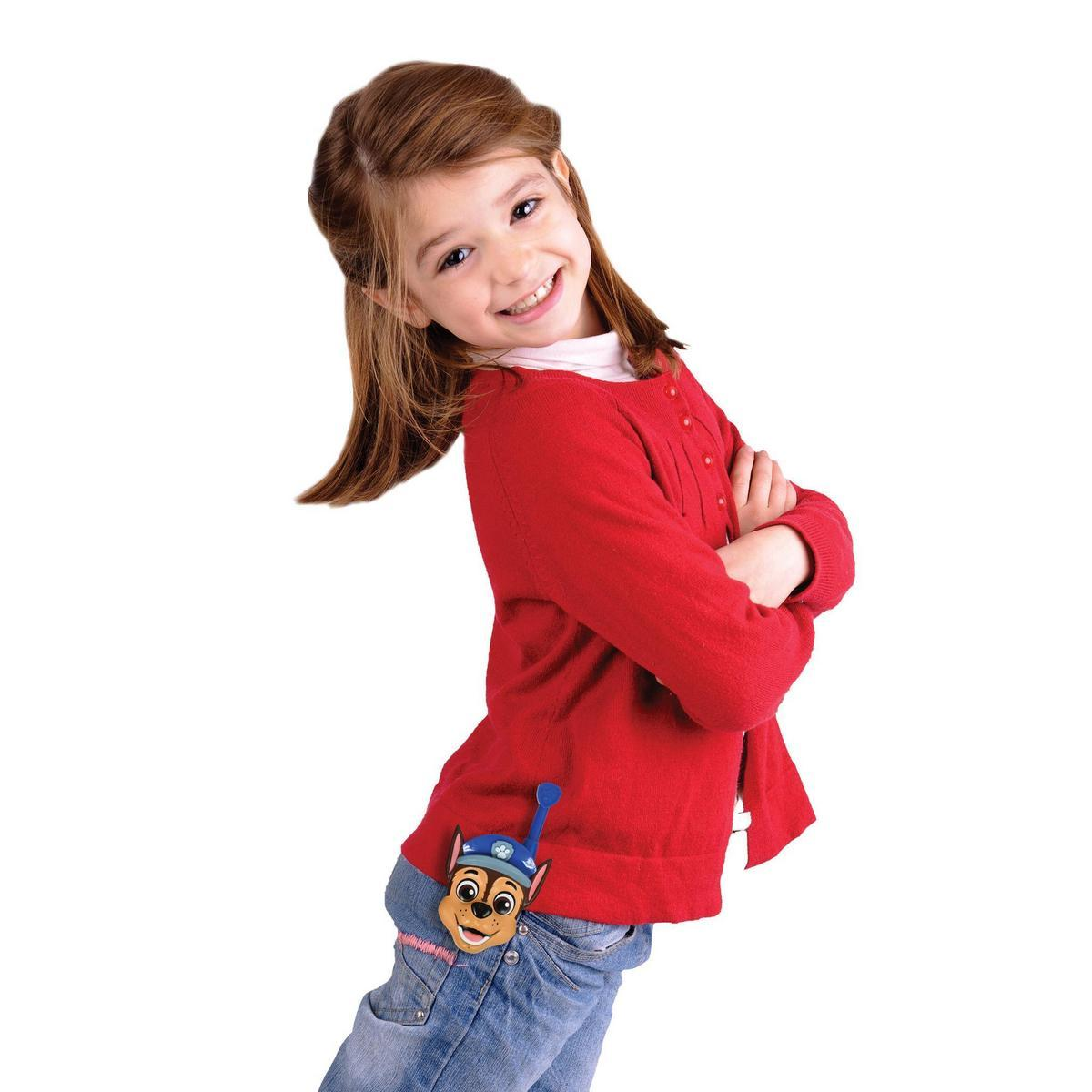 Una niña sonriente con un suéter rojo y jeans tiene los brazos cruzados. Un perro de dibujos animados está sujeto a su bolsillo.