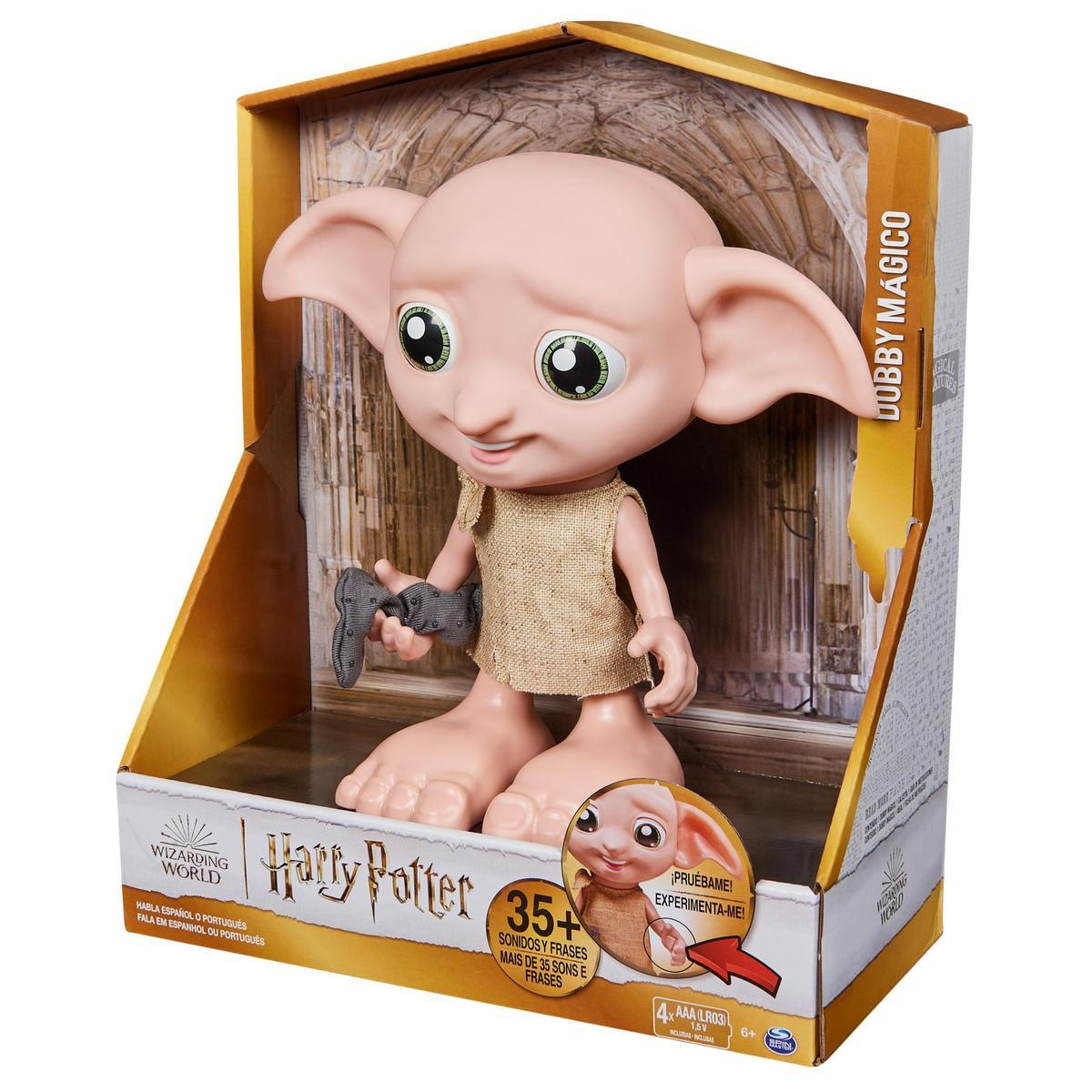 Un juguete de Dobby en una caja. Dobby tiene orejas grandes, ojos verdes y usa un saco de yute. La caja dice Harry Potter y tiene texto en español y portugués.