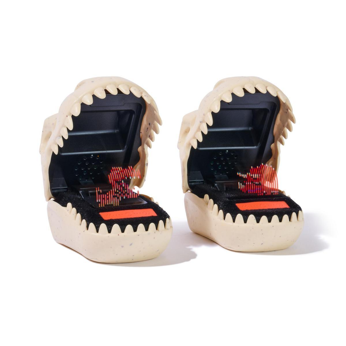 Dos cabezas de juguete de cocodrilo con la boca abierta. Cada una tiene un interior negro y una pantalla roja. Colores beige y negro.