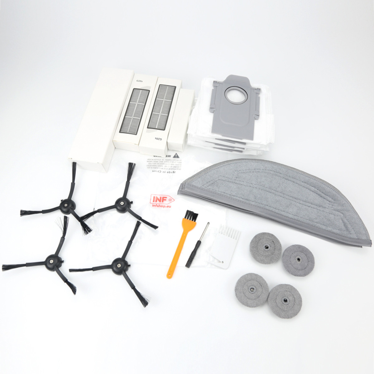 Części robota sprzątającego: szczotki, filtry, narzędzia do czyszczenia, worki na kurz i nakładka do mopa ułożone na białej powierzchni.