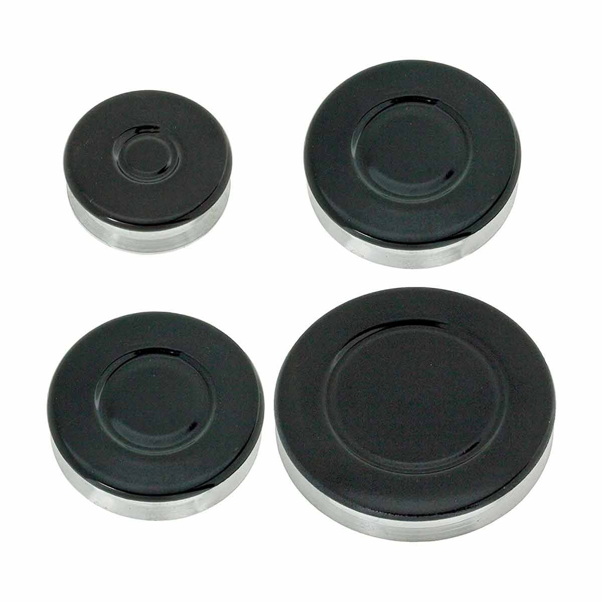 Cuatro cubiertas negras de quemadores de estufa con bordes plateados de varios tamaños se colocan sobre un fondo blanco.