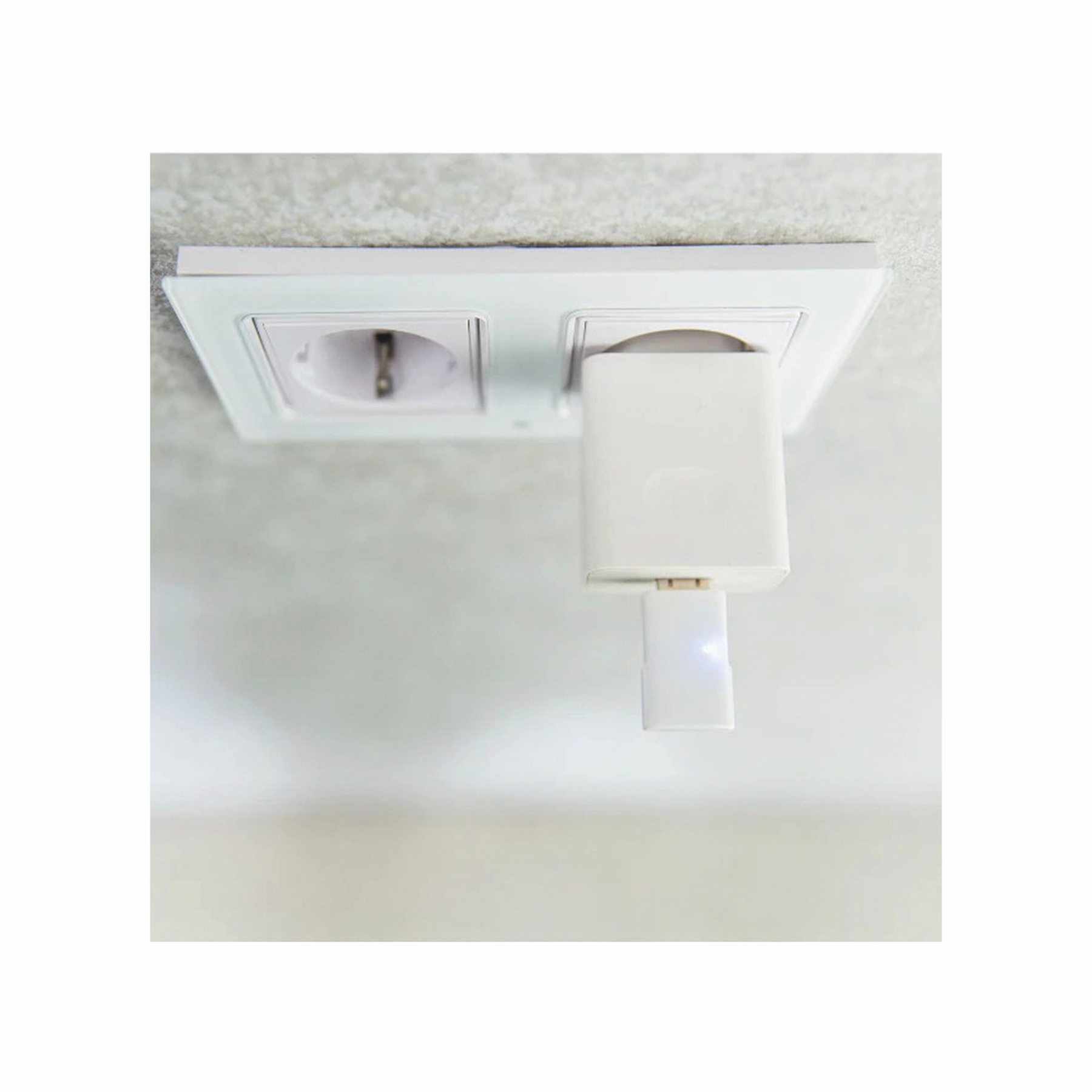 Une prise de courant blanche avec un chargeur blanc branché. Le chargeur a une petite lumière au bout.