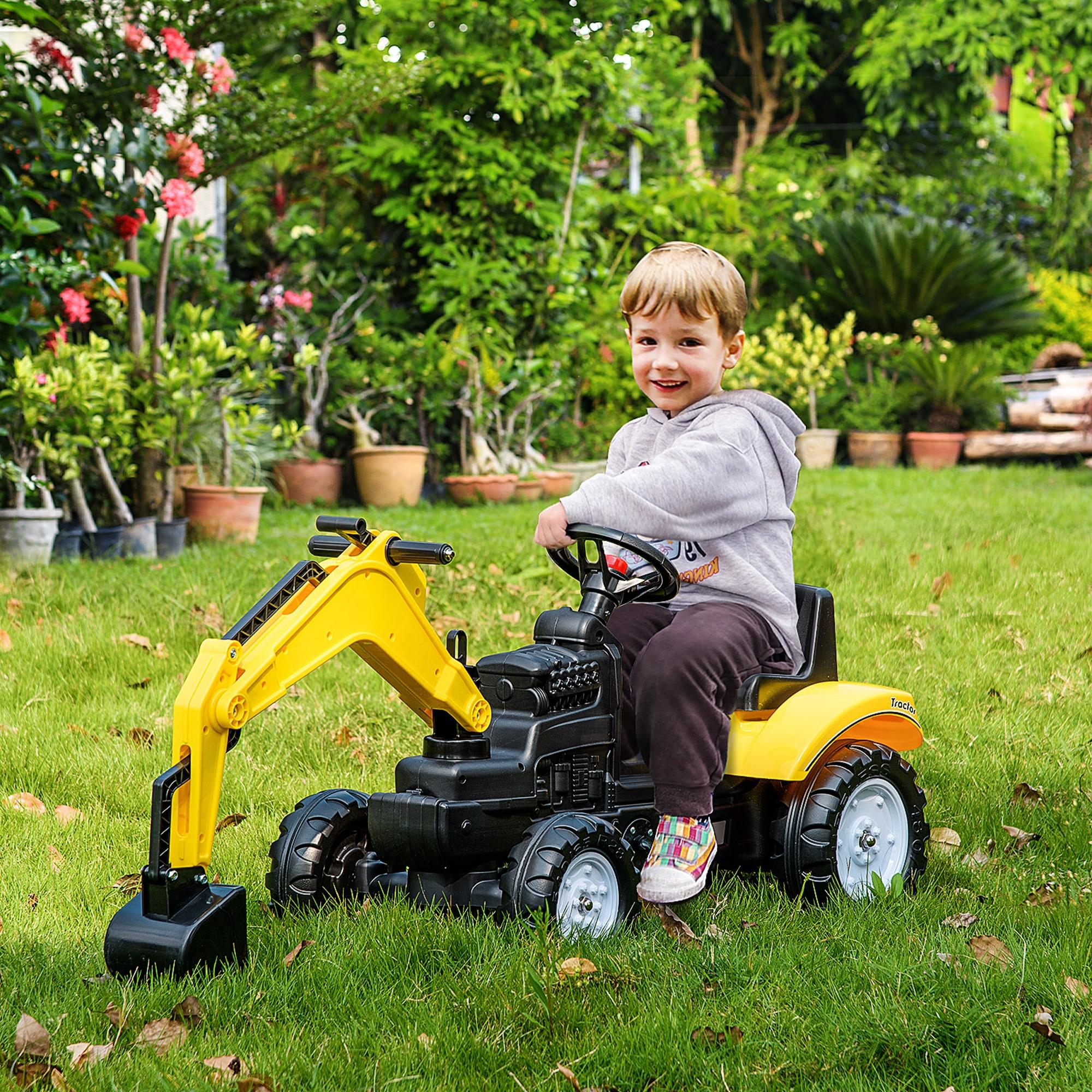 Un bambino sorridente è seduto su un trattore giocattolo giallo e nero in un cortile erboso, circondato da piante e alberi.