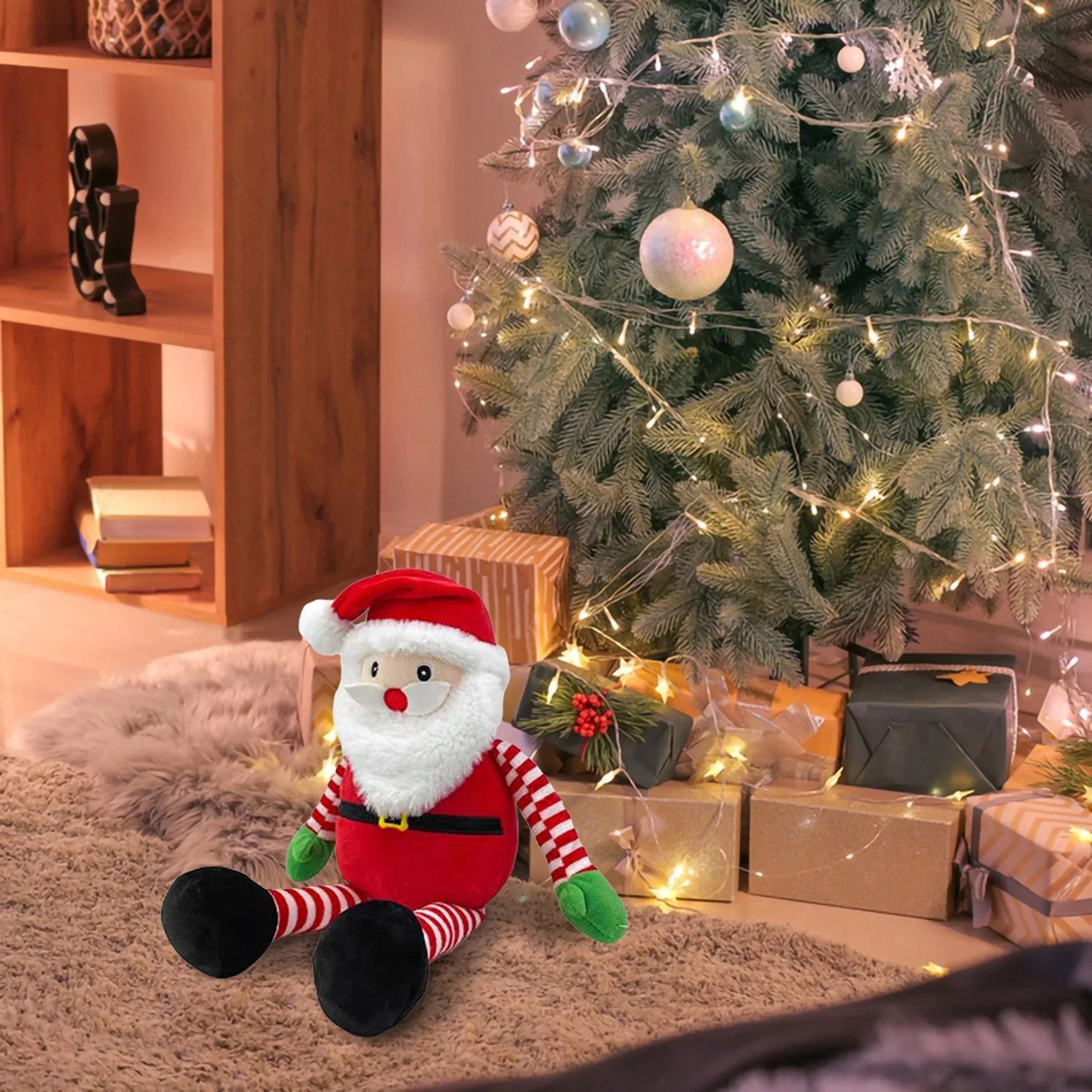 Una muñeca de Papá Noel se sienta frente a un árbol de Navidad con regalos. Hay una estantería a la izquierda.