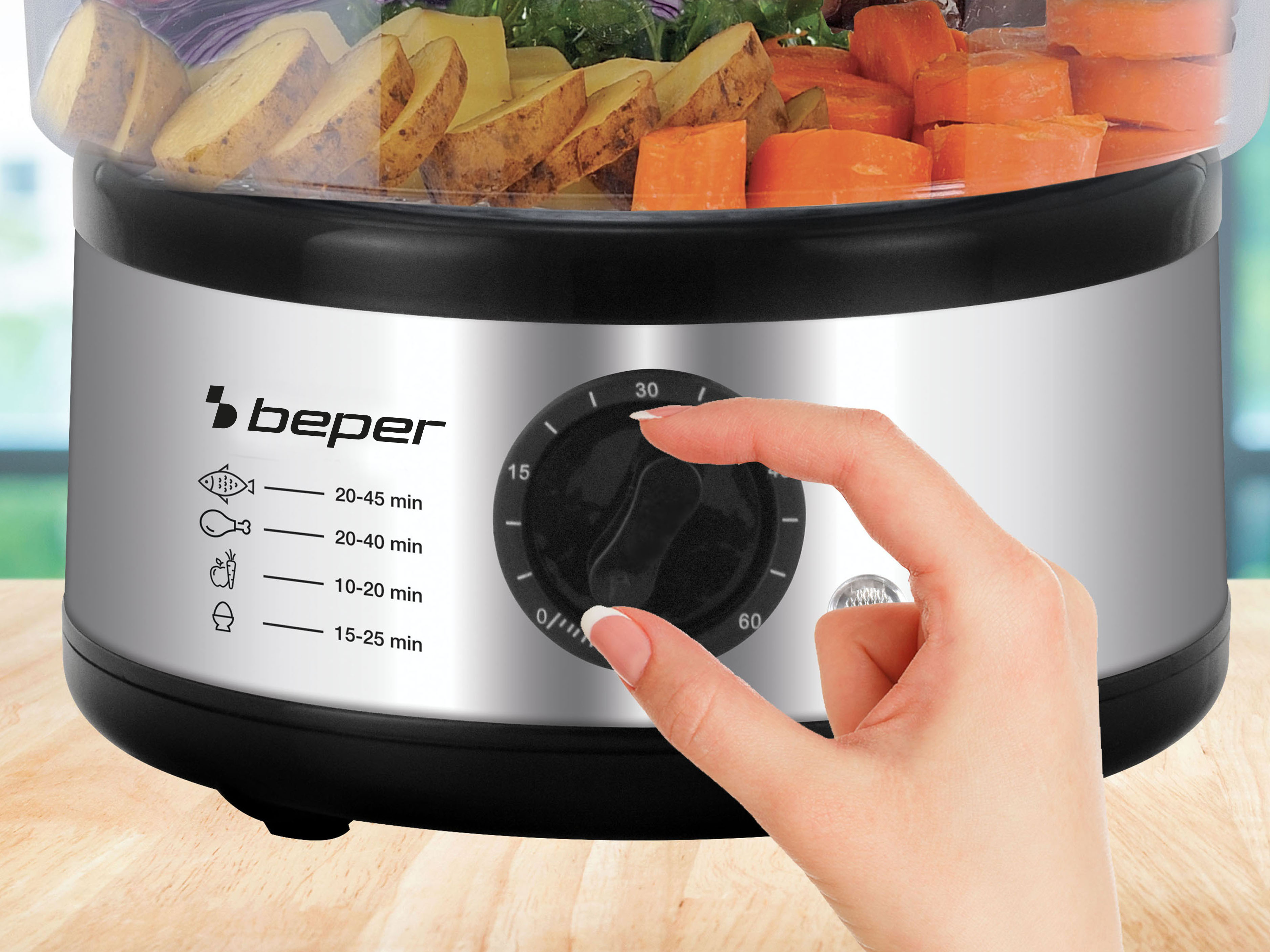 Una vaporiera con verdure. Una mano gira il timer. Si vedono patate e carote.