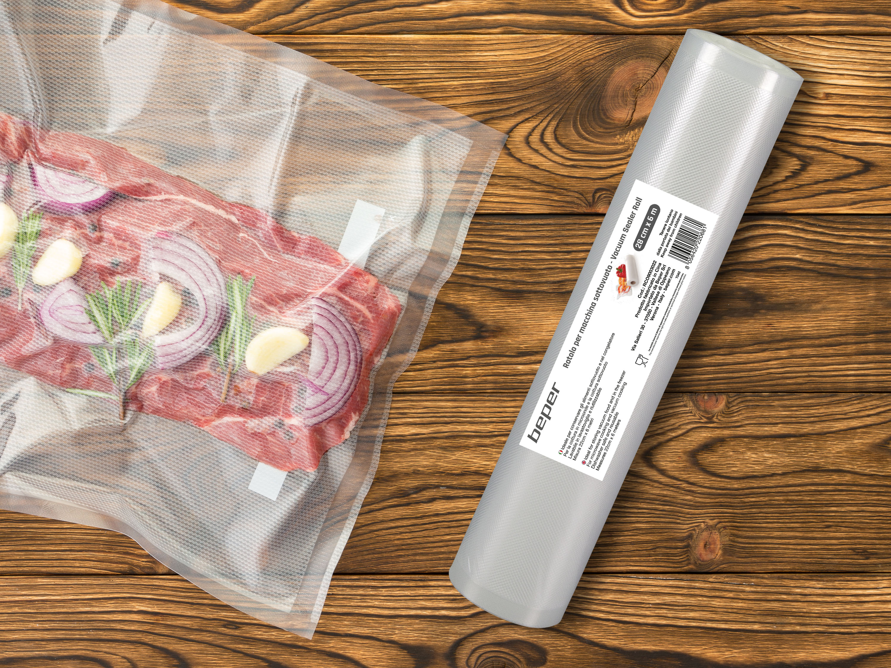 Carne con cipolle, aglio e rosmarino in sacco sottovuoto accanto a rotolo sigillatore, su legno.