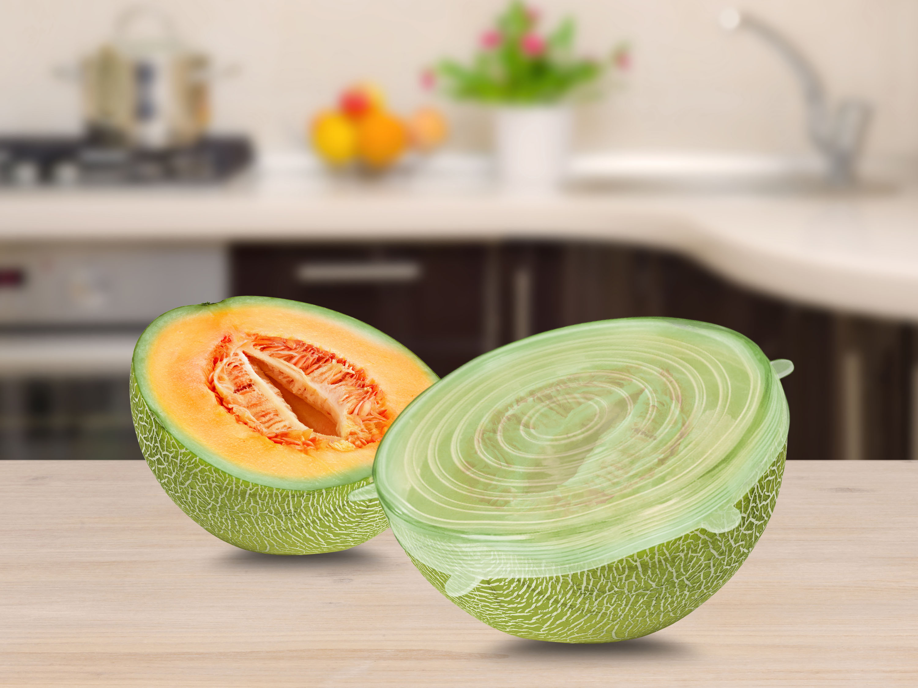 Melone cantalupo a metà su legno. Sfondo cucina sfocato. Una metà mostra polpa arancione, l'altra è verde.