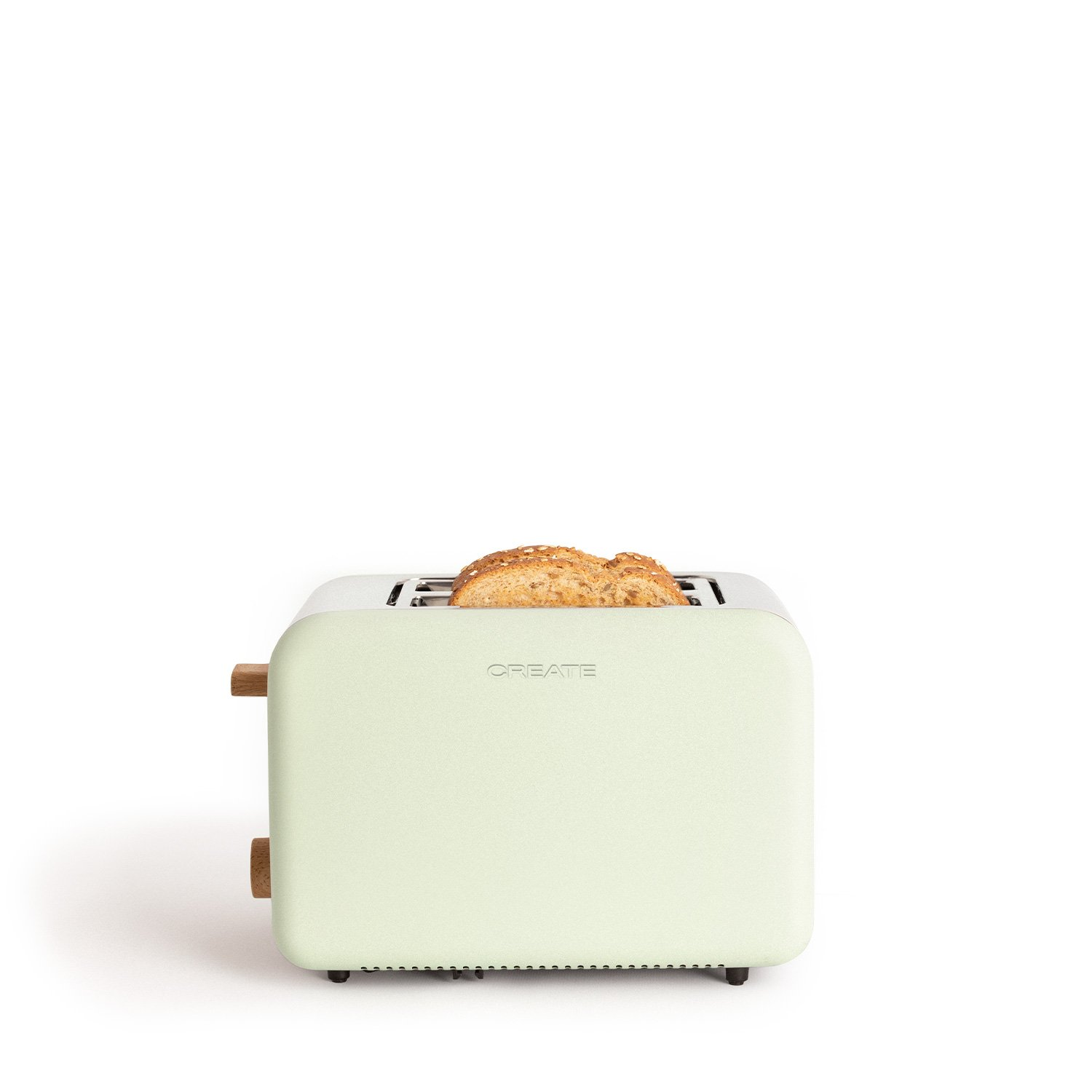 Una tostadora verde menta con mangos de madera y una rebanada de pan tostado. El fondo es blanco.