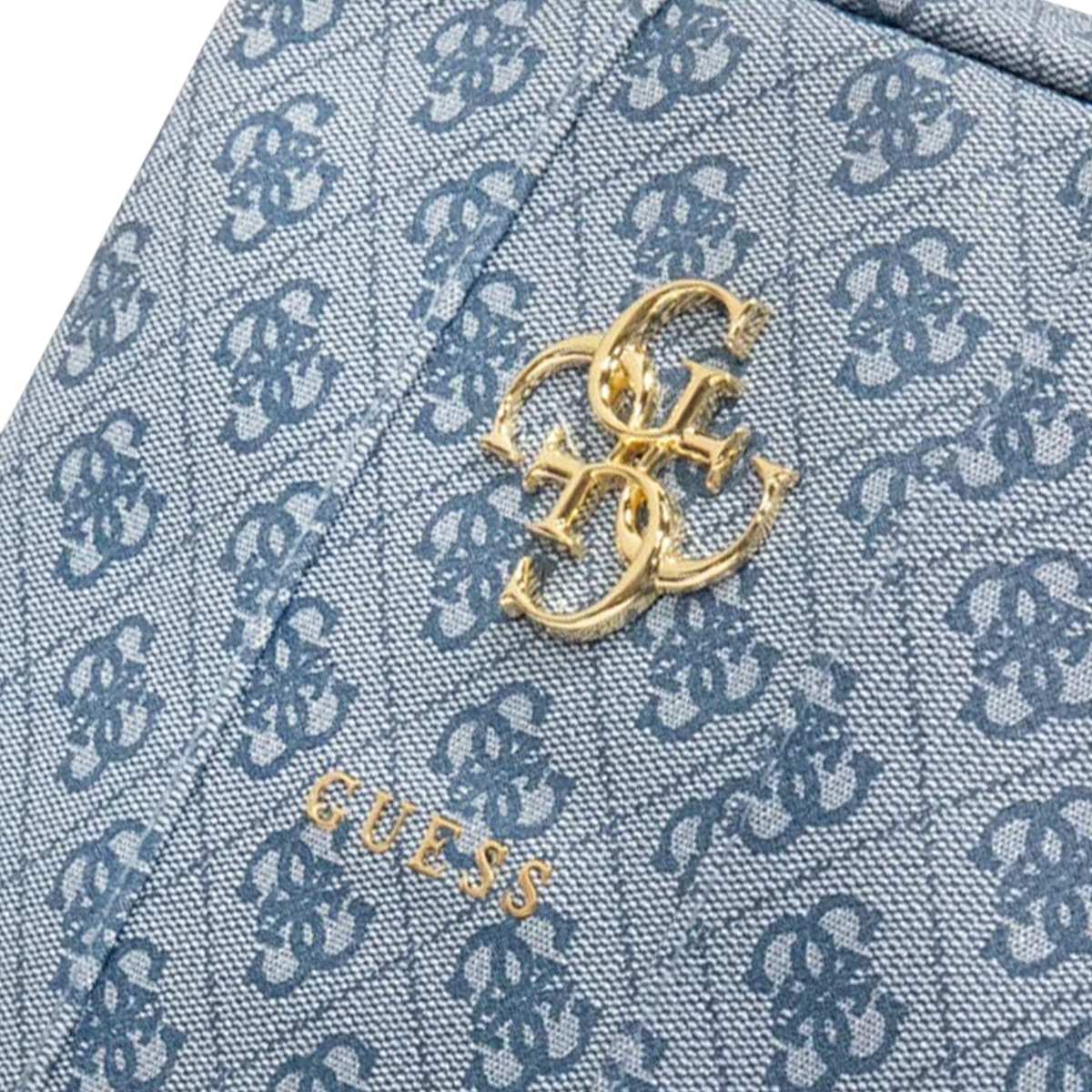 Nahaufnahme einer blauen Guess-Tasche mit goldenem Logo. Die Tasche hat ein sich wiederholendes Muster und das Guess-Logo ist goldfarben.