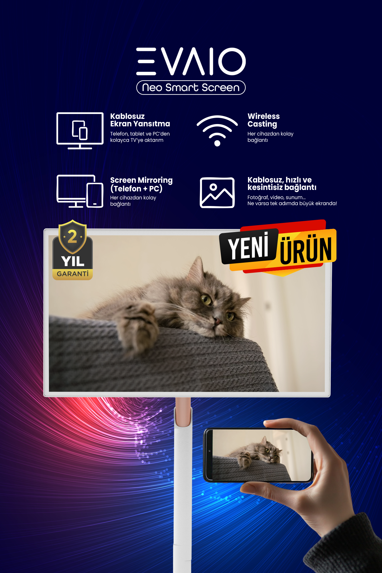 Bir kedi ekranda dinleniyor. Bir el, aynı kediyi gösteren bir telefon tutuyor. Ekran bir stand üzerinde duruyor.