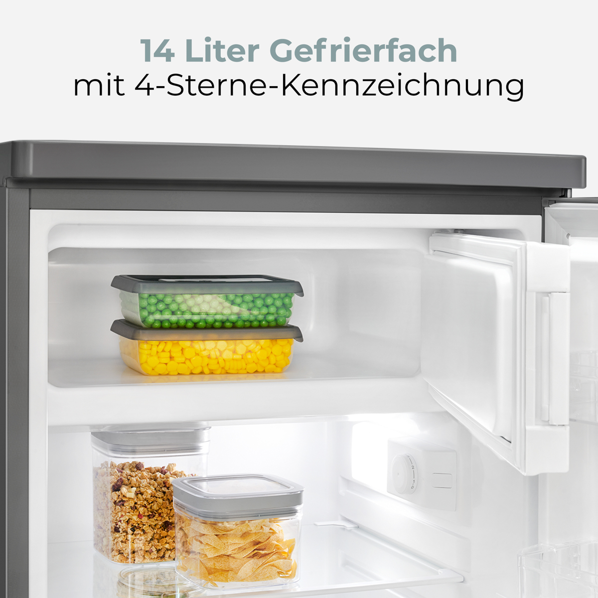 Offener Kühlschrank mit Behältern mit Erbsen und Mais, sowie Müsli und Chips. Gefriertür offen. Text: 14 Liter Gefrierfach.